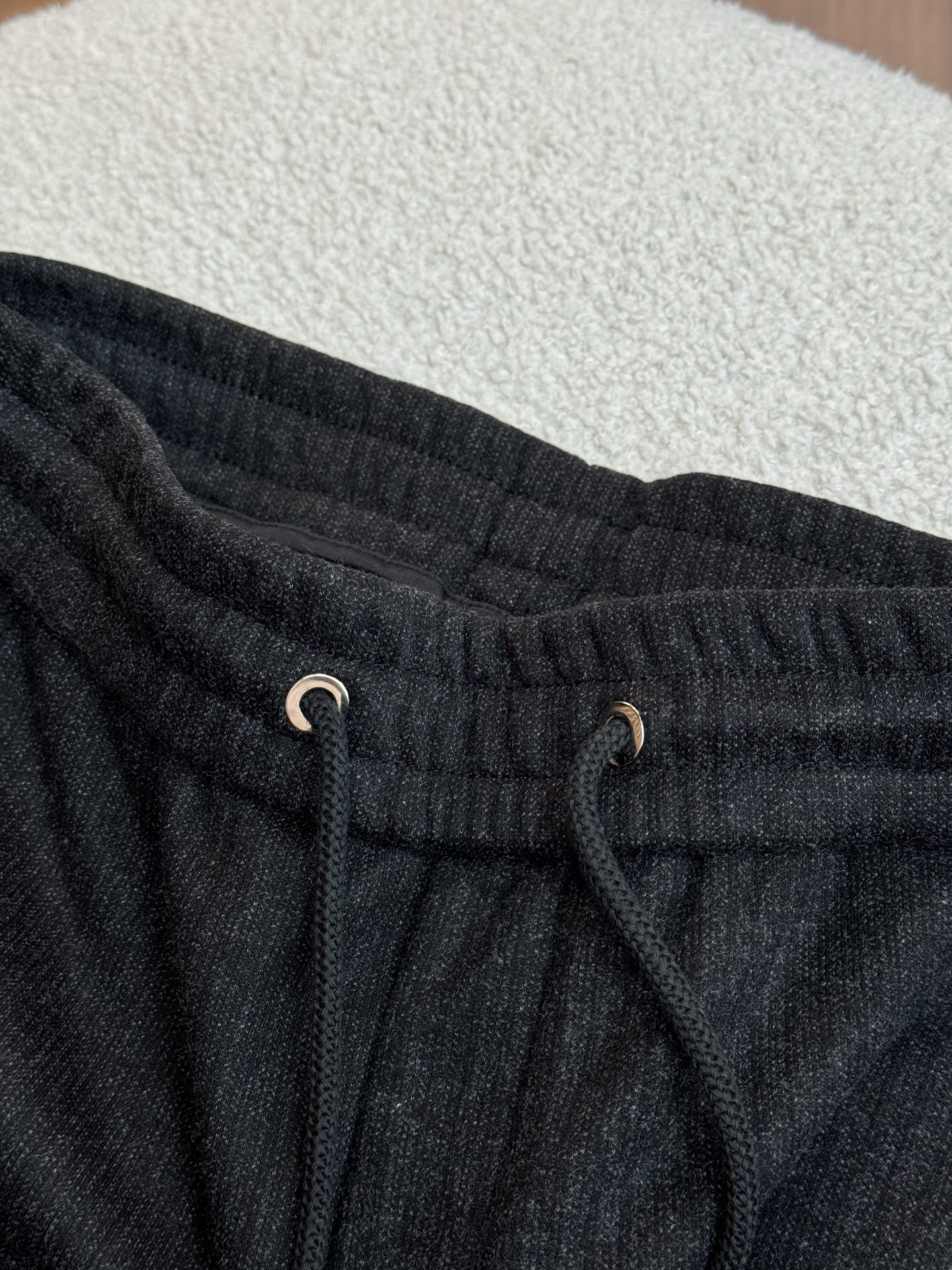 采用抽绳设计，抽绳为黑色编织绳，两端搭配金属质感的圆柱型绳头