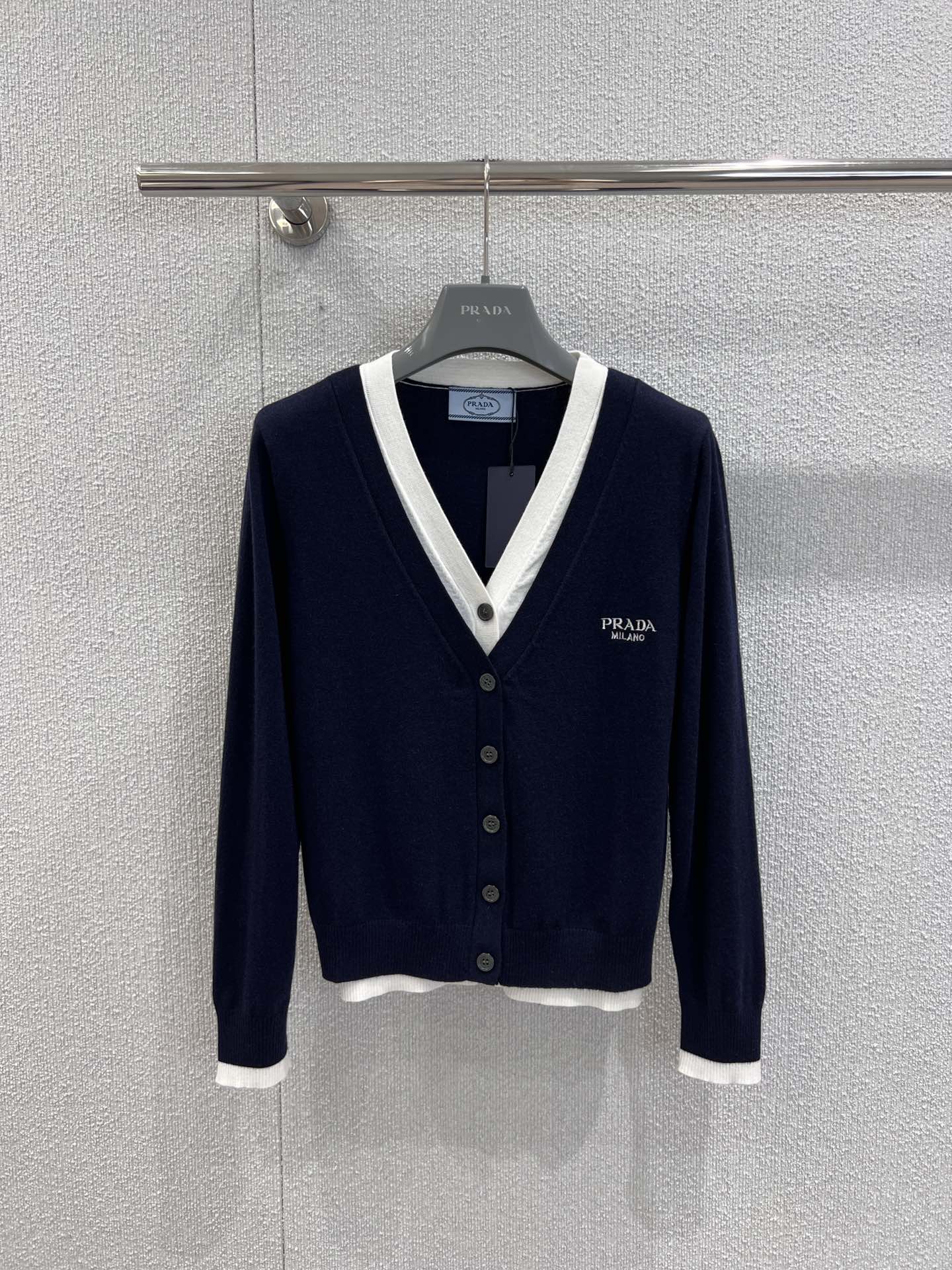 NO:491145,Support replacement Prad* 25Fw early autumn new model, micro-label embroidered fake two-piece knitted cardigan丨Exclusive high-end product!  The main color of Navy is cleverly integrated into the white inner splicing design to create a layered layering, simple and high-end. The classic V-neck modifies the neck line, and the brand logo on the chest is low-key to indicate identity, highlighting the light luxury texture. The single-breasted design is neat and elegant, with a slim cut out the beautiful figure, and a soft and skin-friendly knitted material is very suitable for both inner and outer wear. It is easy to adapt to workplace, date and other occasions, adding a touch of elegance and elegance to your outfit. S/M/L real-life details pictures, prada, alexander wang19860909支持换款 Prad* 25Fw早秋新款 微标刺绣假两件针织开衫丨独家高版出品！以藏青为主色调,巧妙融入白色内层拼接设计,打造出叠穿般的层次感,简约又不失高级感.经典 V 领修饰颈部线条,胸口的品牌徽标低调点明身份,彰显轻奢质感.单排扣设计利落大方,修身剪裁勾勒优美身形,柔软亲肤的针织材质,无论是内搭还是外穿都很合适,轻松适配职场、约会等多种场合,为你的穿搭增添一份精致与优雅. 现货发售S/M/L实拍细节图,,prada,alexander wang,Women's clothing