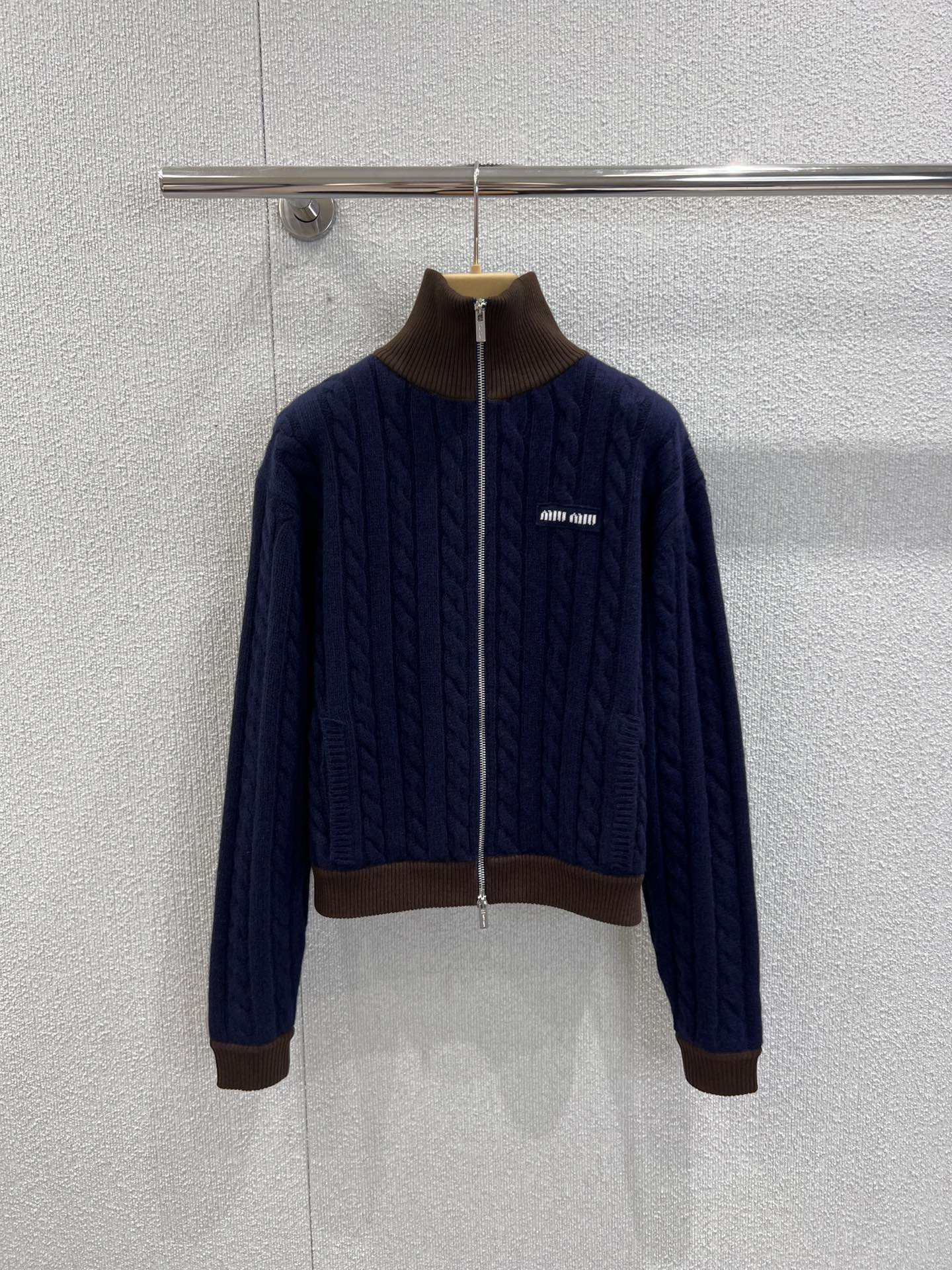 NO:570775,Support exchange of MiuMiu 25FW new autumn and winter micro-label cable wool knitted cardigan丨exclusively developed by yb!  High quality production!  Adopting classic cable knitting technology, the navy blue wool fabric has its own delicate texture, visually it is the gentleness of retro college style, and the touch is the warmth and softness of wool material. The full zipper design makes it salty or sweet, and the dark brown and navy blue collar and cuff design instantly break the monotony of monochrome knitting. The layers are clear and the retro charm is hidden, making the overall look more memorable. Ready-made S/M/L real shot details, miumiu, alexander wang19860909支持换款MiuMiu 25FW秋冬新款 微标绞花羊毛针织开衫丨独家yb开发！高版出品！采用经典绞花针织工艺,藏蓝色羊毛面料自带细腻肌理感,视觉上是复古学院风的温柔,触觉上是羊毛材质的温暖软糯.全拉链设计让它可盐可甜,深棕撞藏蓝的领边、袖口设计,瞬间打破单色针织的单调感,层次分明又暗藏复古小心机,让整体造型更具记忆点.现货发售S/M/L实拍细节图,,miumiu,alexander wang,Women's clothing
