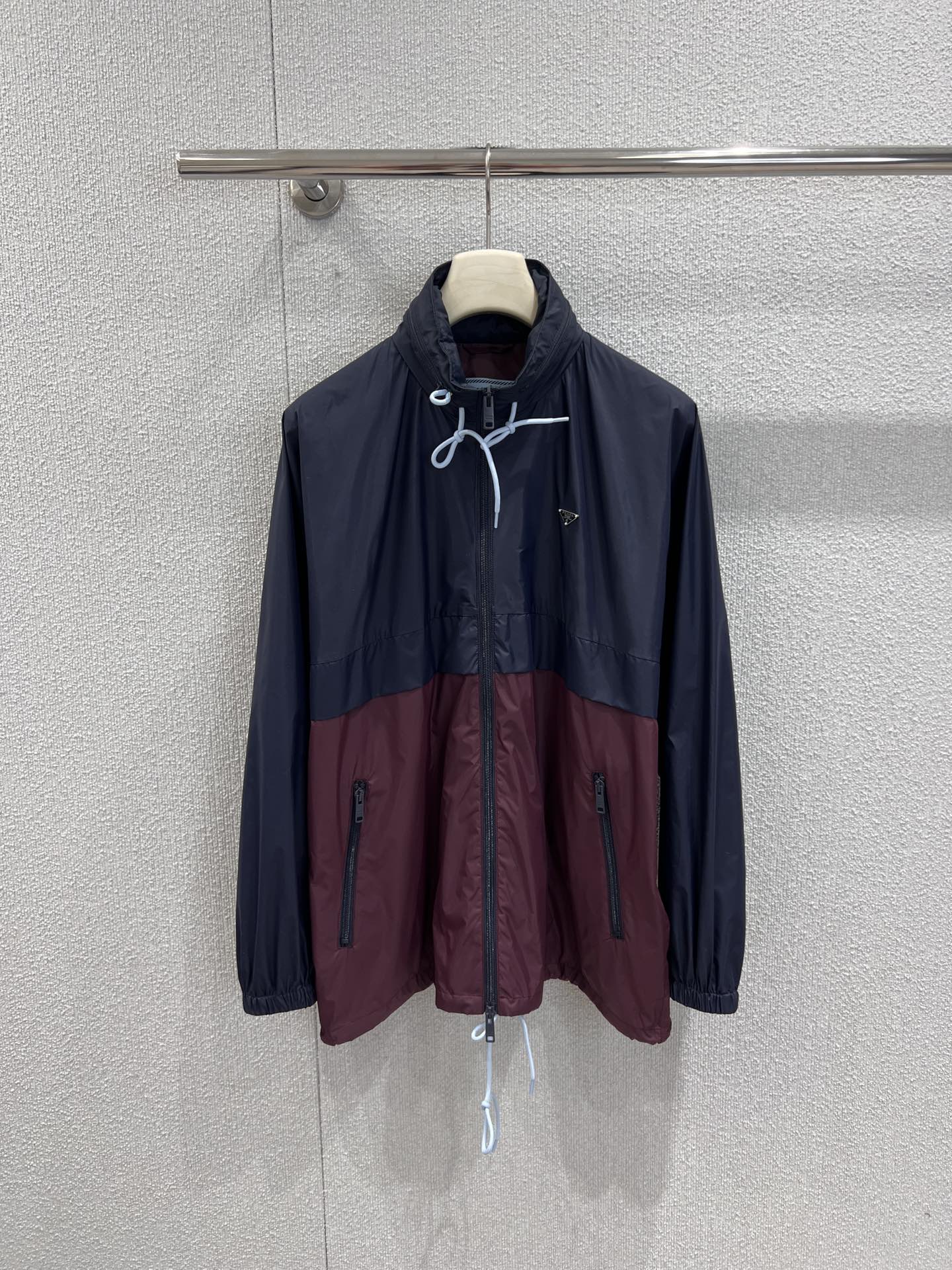 NO:665914,Support exchange Prad* 26SS early spring new style dark blue with burgundy triangle logo long drawstring hooded windbreaker丨Exclusively developed by yb!  Top quality production!  The color matching design of dark blue and burgundy breaks the monotony, and the classic triangle logo hides the brand style. The long cut is paired with a drawstring hood design, which is both practical and stylish. The light and windproof fabric is suitable for the changeable weather in early spring, making it easy to wear a casual and high-end modern style. Ready-made S/M/L real shot details, prada, hats,  19860909支持换款 Prad* 26SS早春新款 深蓝拼酒红三角标长款抽绳连帽风衣丨独家yb开发！顶级高版出品！深蓝撞酒红的拼色设计打破单调,经典三角标暗藏品牌格调,长款剪裁搭配抽绳连帽设计,兼具实用性与造型感,轻盈防风的面料适配早春多变天气,轻松穿出随性高级的摩登范.现货发售S/M/L实拍细节图,,prada,hats, ,Women's clothing