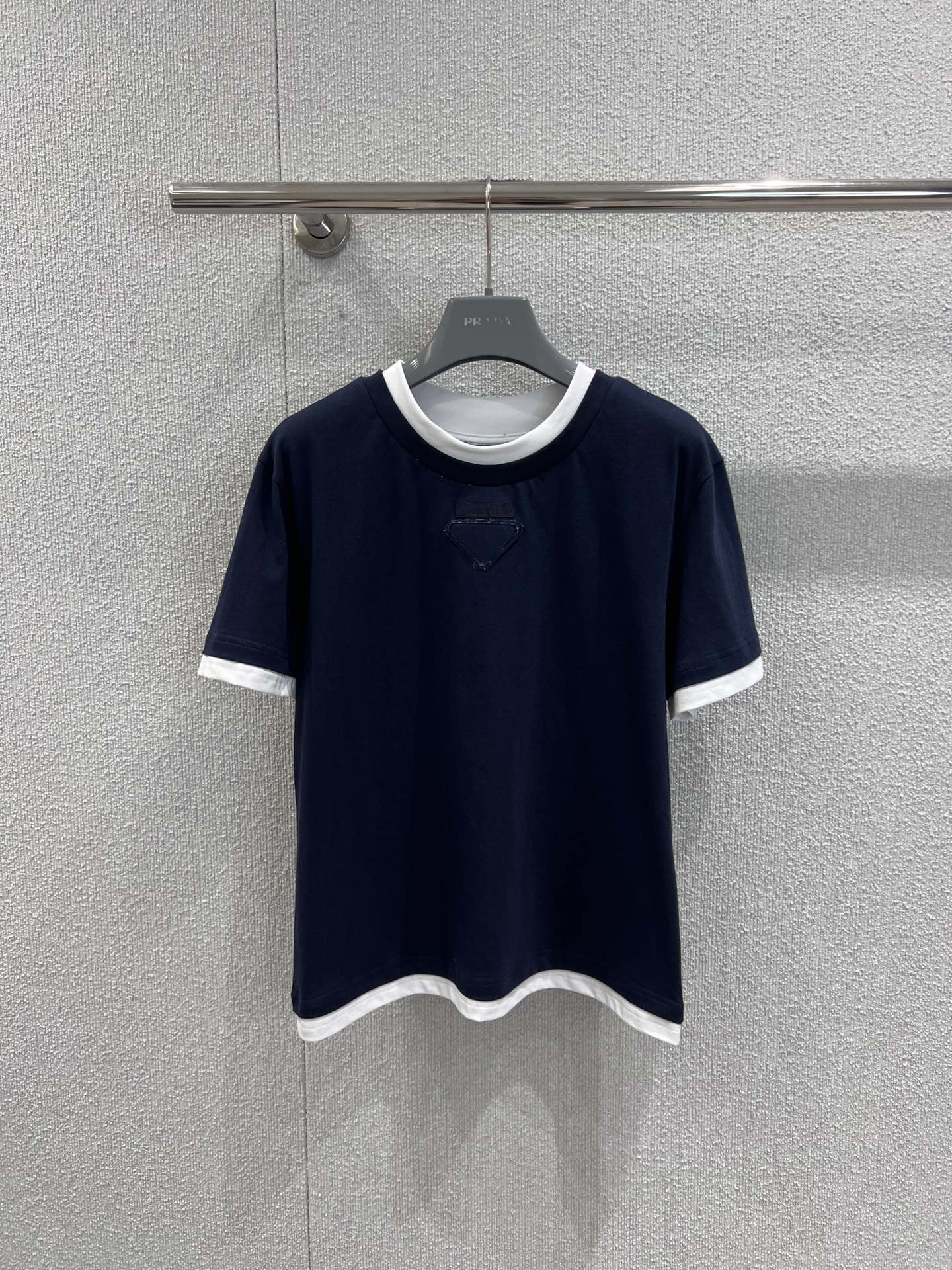 NO:685451,Support exchange Pra*a 26SS early spring new loose fake two-piece round neck short-sleeved T-shirt丨Exclusive high-end version!  Minimalist design combined with ingenious details. Two pieces of contrasting trim break the monotony of the basic model. The three-dimensional triangle logo hides brand recognition. Soft cotton fabric is selected to create a loose silhouette, which is skin-friendly, breathable and highly tolerant to the body shape. Available in navy blue and gray.  The classic colors are versatile and easy to wear. It is a basic luxury model that combines simple style and practicality for daily wear in early spring. Ready-made S/M/L real shot details, prada, T-shirt, tees, t-shirt,19860909支持换款 Pra*a 26SS早春新款 宽松假两件圆领短袖T恤丨独家高版出品！以极简设计糅合巧思细节.假两件撞色边饰打破基础款的单调,立体三角标识暗藏品牌辨识度,甄选柔软棉质面料打造宽松廓形,亲肤透气且对身形包容度极高.藏青与灰色两大经典色系百搭不挑人,是早春日常穿搭中兼具简约格调与实穿性的奢品基础款.现货发售S/M/L实拍细节图,,prada,T-shirt,tees，t-shirt,,Women's clothing