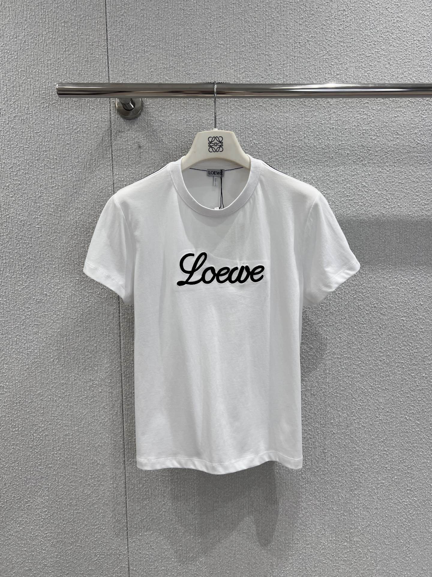 NO:687644,Supports exchange Loew* 26Ss spring and summer new style simple letter LOGO line short-sleeved T-shirt丨Exclusively developed by yb!  High quality production!  A minimalist design outlines a light and luxurious texture. The classic white T base is matched with the brand letters LOGO outlined in three-dimensional lines, breaking the monotony of flat printing and making the logo more layered. The soft and skin-friendly cotton fabric is both breathable and comfortable, suitable for daily wear in spring and summer. The loose version does not pick on the body shape and can be matched casually.  Denim skirts, wide-leg pants or casual shorts can easily create a lazy and sophisticated high-street style. They are versatile and light luxury items that are indispensable in the wardrobe. Ready-made S/M/L real shot details, loewe, skirts, shorts, T-shirt, tees, t-shirt,19860909支持换款 Loew* 26Ss春夏新款 简约字母LOGO线条短袖T恤丨独家yb开发！高版出品！以极简设计勾勒轻奢质感.经典白T基底搭配立体线条勾勒的品牌字母LOGO,打破平面印花的单调,让标识感更具层次；柔软亲肤的棉质面料,兼顾透气与舒适度,适配春夏日常多场景穿搭.宽松的版型不挑身形,可随性搭配牛仔半裙、阔腿裤或休闲短裤,轻松打造慵懒又精致的高街风格,是衣橱里不可缺少的百搭轻奢单品.现货发售S/M/L实拍细节图,,loewe,skirts,shorts,T-shirt,tees，t-shirt,,Women's clothing