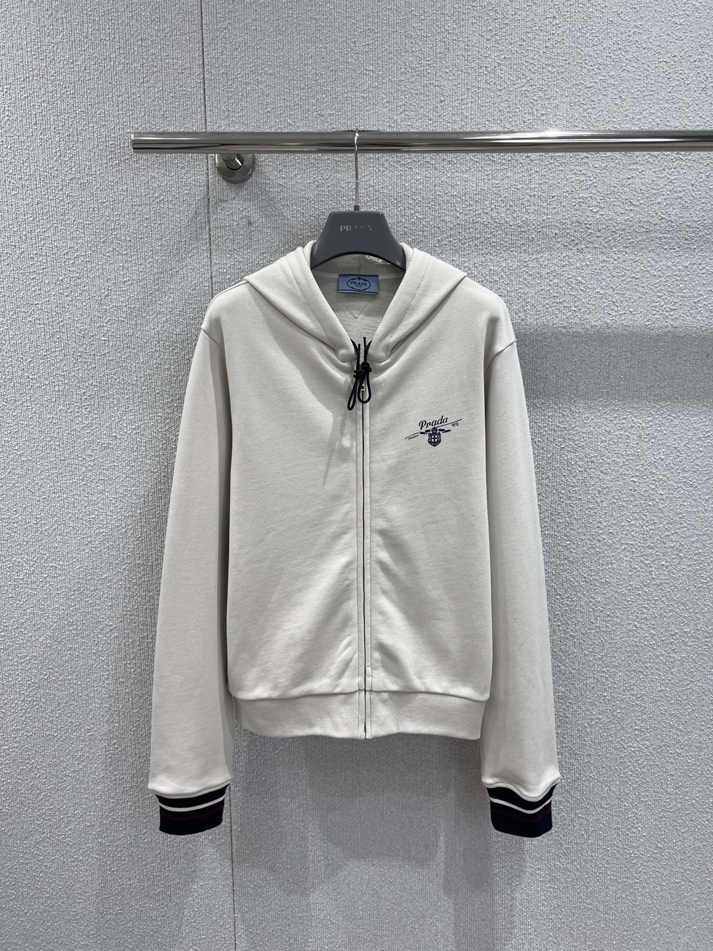 NO:697431,Supports exchange Prad* 25Fw new autumn and winter college style letter print zipper hooded sweatshirt jacket丨Exclusively developed by yb!  Top quality production!  Perfect the balance between laziness and sophistication!  The off-white tone is gentle and versatile, and the soft cotton fabric is skin-friendly and breathable, so it is not stuffy at all in autumn and winter. The classic hooded design is equipped with a full zipper closure, which can be easily put on and taken off and can create a casual look with a half-open collar; the contrasting stripes on the cuffs echo the delicate letter print on the body, instantly adding a college-style atmosphere, and the short silhouette can also be optimized  Body proportions. Paired with a pleated skirt, it is exclusive to sweet girls. Paired with wide-leg pants, it can also unlock a cool street feel. One piece can cover all the fashionable casual styles in autumn and winter ~ Ready stock S/M/L real shot details, prada, hoodie, sweatshirts, skirts, jackets  & coats,hats,19860909支持换款 Prad* 25Fw秋冬新款 学院风字母印花拉链连帽卫衣外套丨独家yb开发！顶级高版出品！把慵懒与精致的平衡玩到极致！米白色调温柔又百搭,软糯的棉质面料亲肤又透气,秋冬穿完全不闷.经典连帽设计搭配全拉链开合,穿脱自如还能打造半开领的随性造型；袖口撞色条纹与衣身精致的字母印花相呼应,瞬间拉满学院风氛围,短款廓形还能优化身材比例.搭百褶裙是甜妹专属,配阔腿裤又能解锁酷飒街头感,一件承包秋冬所有休闲造型的时髦度～现货发售S/M/L实拍细节图,,prada,hoodie,sweatshirts,skirts,jackets & coats,hats,,Women's clothing