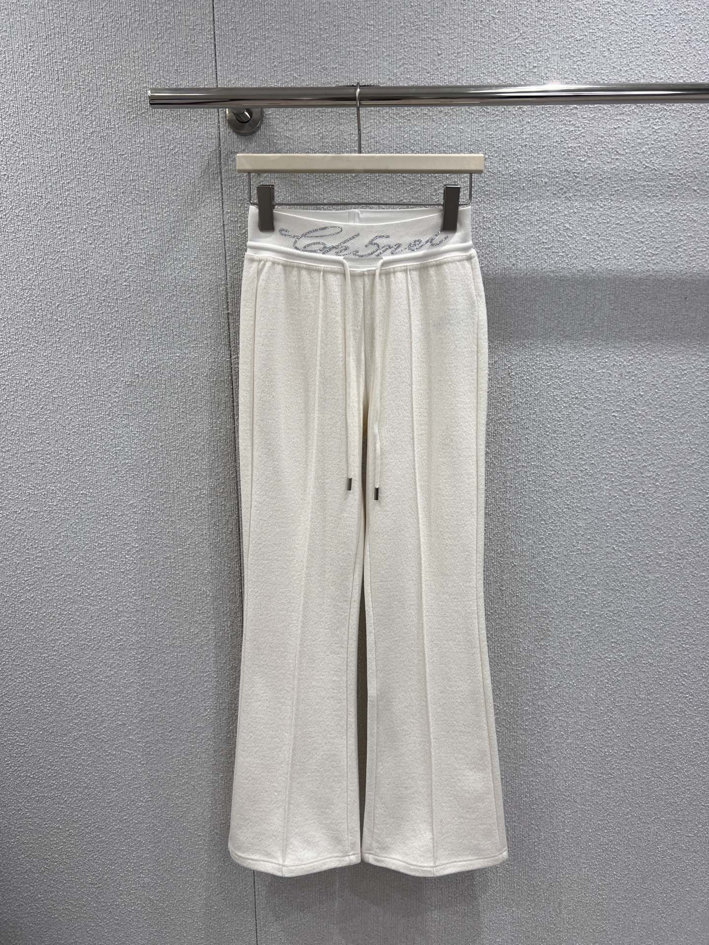 NO:697721,Supports exchange Cha*el 25Fw new autumn and winter style casual trousers with rhinestoned letter waistband丨Exclusive high-end version!  The classic black and white two-color interpretation of French elegance. The hot-drilling process of the brand letters on the waist is the finishing touch. The Swarovski rhinestones are inlaid and arranged by hand, reflecting the delicate and bright luster under the light, showing the exquisite craftsmanship of the haute couture workshop. The matte knitted wool fabric is selected and brushed to feel soft and warm, with both drape and shaping ability.  ; The high-waisted and slightly flared version cleverly raises the waistline, and the natural drape lines from the waist to the trouser legs modify the proportions of the legs. The loose trousers accommodate the shape of the legs and can be perfectly matched with short tops, sweaters and other items, injecting a lazy and high-end modern style into the autumn and winter looks. Ready-made S/M/L real shot details,,swarovski,19860909支持换款 Cha*el 25Fw秋冬新款 字母烫钻腰头休闲长裤丨独家高版出品！以经典黑白双色诠释法式奢雅,腰头处的品牌字母烫钻工艺堪称点睛之笔,施华洛世奇水钻经手工镶嵌排列,在光线下折射出细腻璀璨的光泽,尽显高定工坊的精湛匠艺.精选哑光针织羊毛面料,经磨毛处理后触感软糯温暖,兼具垂坠感与塑形力；高腰微喇版型巧妙拉高腰线,从腰腹到裤脚的自然垂坠线条修饰腿部比例,宽松裤管包容腿型的同时,又能与短上衣、针织衫等单品完美搭配,为秋冬造型注入慵懒又高级的摩登格调.现货发售S/M/L实拍细节图,,swarovski,,Women's clothing