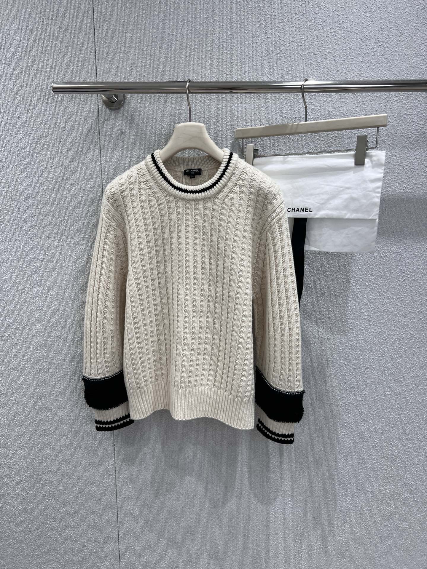 NO:708983,Support exchange Chane* 25N ski season new round neck college style wool sweater丨Exclusively developed by yb!  Top quality production!  Wang Yibo's same style redefines the aesthetics of light luxury knitting in winter. The iconic contrasting colors of off-white and black, and the three-dimensional cable knitting technology make the body full of texture. The merino wool fabric has both warmth and breathability, making it unrestricted when worn in winter. The black plush splicing and striped webbing on the cuffs,  Give the basic style a unique fashion charm, with sophisticated overlocking technology and invisible stitching. The double C jacquard on the back is outlined with stitches of the same color, which is low-key yet recognizable. An indispensable winter treasure item in the wardrobe. Ready-made S/M/L real shot details,,chanel,19860909支持换款 Chane* 25N滑雪季新款 圆领学院风羊毛针织衫丨独家yb开发！顶级高版出品！王一博同款重新定义冬日轻奢针织的穿搭美学.标志性的米白与黑色撞色,立体绞花针织工艺让衣身肌理感十足,美利奴羊毛面料兼具保暖性与透气性,冬日穿着无束缚感.袖口的黑色毛绒拼接与条纹织带,让基础款型焕发独特的时尚魅力,精密的锁边工艺与隐形车线,后背的双C提花以同色系线迹勾勒,低调又不失辨识度.衣橱中不可或缺的冬日宝藏单品.现货发售S/M/L实拍细节图,,chanel,,Women's clothing