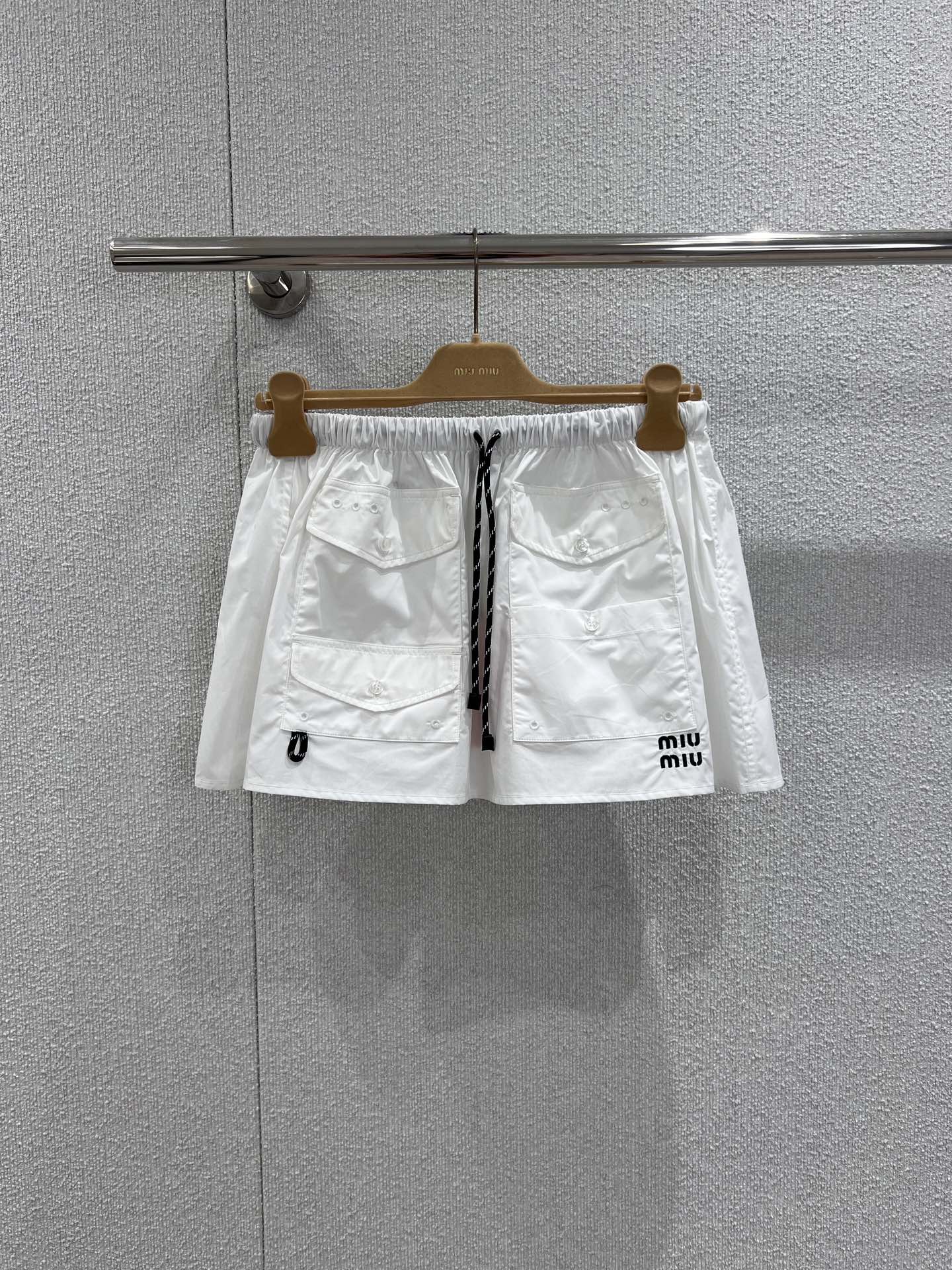 NO:708995,Supports exchange Miumi* 26Ss early spring new style letter logo pocket mini skirt丨Exclusively developed by yb!  Top quality production!  Made of crisp cotton poplin, it creates an A-line silhouette that has both a workwear feel and a girly feel. The drawstring design at the waist can be adjusted freely to suit different waist sizes; the multi-pocket details echo the mini letter logo on the side, injecting retro vitality into the pure white skirt. Whether it is paired with a velvet sweater to create a sweet look  Cool college style, or combined with a short vest for a hot girl look, it can be the finishing touch of an early spring look, easily balancing relaxation and sophistication. Ready-made S/M/L real shot details, miumiu, hoodie, sweatshirts, skirts,19860909支持换款 Miumi* 26Ss早春新款 字母徽标口袋迷你半身裙丨独家yb开发！顶级高版出品！以挺括的棉质府绸为面料,打造出兼具工装感与少女感的A字廓形.腰部的抽绳设计可自由调节松紧,适配不同腰围；多口袋细节与侧边的迷你字母徽标相呼应,为纯白裙身注入复古活力.无论是搭配丝绒卫衣打造甜酷学院风,还是与短款背心组合出辣妹感,它都能成为早春造型的点睛之笔,轻松平衡松弛感与精致感.现货发售S/M/L实拍细节图,,miumiu,hoodie,sweatshirts,skirts,,Women's clothing