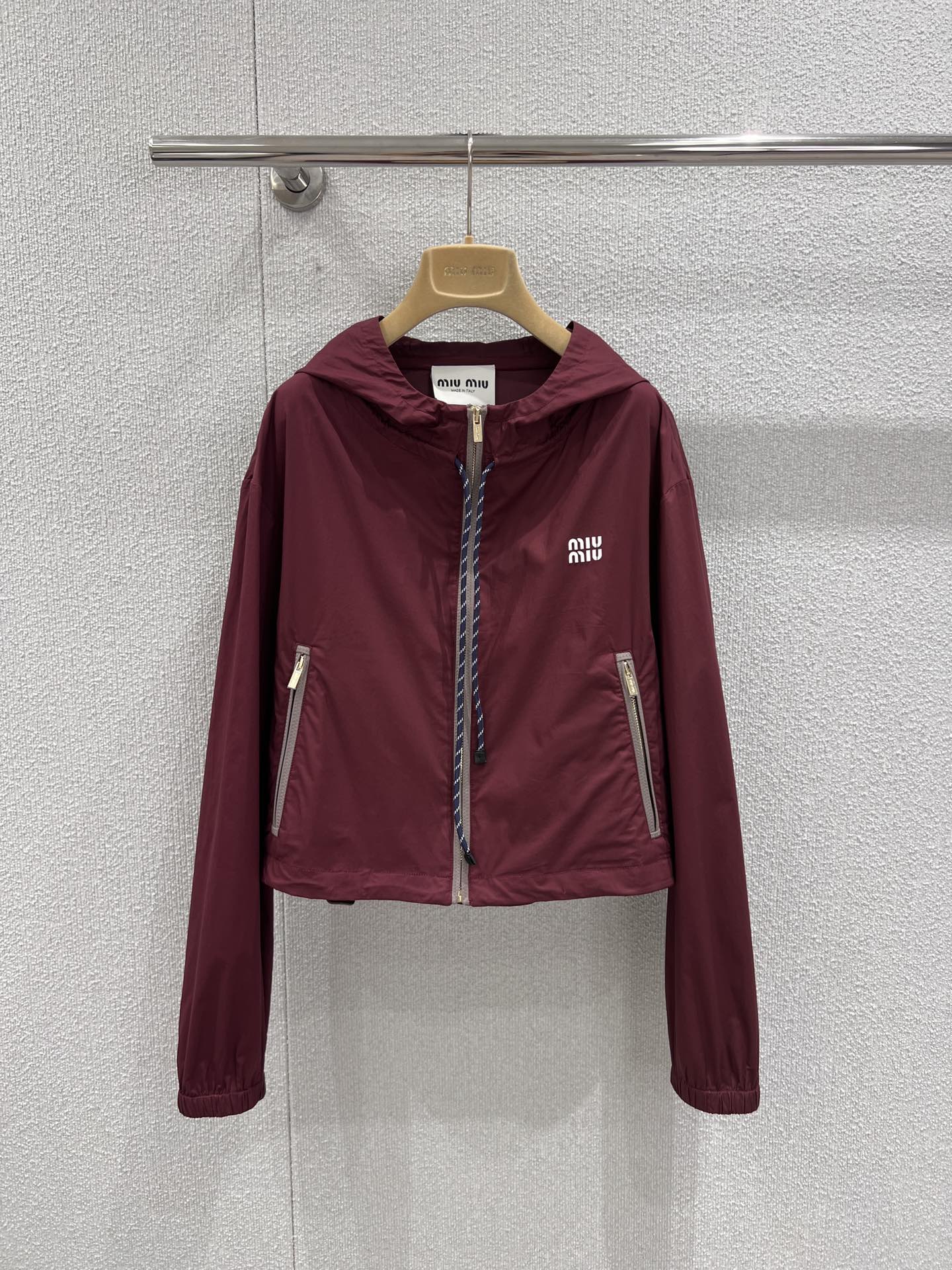 NO:709625,Jackets support exchange Miu Mi* 26Ss early spring new style burgundy hooded micro-label jacket jacket + shorts set丨Exclusively developed by yb!  Top quality production!  The main color is retro and rich burgundy. The light nylon fabric has a delicate luster and is windproof and breathable. It is an excellent choice for the change of seasons in early spring. The hooded jacket adopts a loose shoulder cut, with a drawstring design and a contrasting zipper, integrating exquisite details into the casual sports style. The shorts of the same series continue the design language of the jacket.  The side zipper and drawstring waistband are both practical and stylish. The whole set does not need to be thought about, and it is easy to create a relaxed and fashionable sweet and cool girly look. Whether worn alone or layered, it can become the focus of attention on the streets in early spring. Ready-made S/M/L real shot details,, miumiu, shorts, jackets  & coats,jackets & coats,hats,19860909外套 支持换款 Miu Mi* 26Ss早春新款 酒红色连帽微标夹克外套+短裤套装丨独家yb开发！顶级高版出品！以复古浓郁的酒红色为主调,轻盈的尼龙面料自带细腻光泽感,兼具防风性与透气性,是早春换季的绝佳选择.连帽夹克采用宽松落肩剪裁,搭配抽绳设计与撞色包边拉链,在休闲运动风中融入精致细节；同系列短裤延续了夹克的设计语言,侧边拉链与抽绳腰头兼具实用性与造型感.整套搭配无需费心思考,轻松打造松弛又时髦的甜酷少女感,无论是单穿还是叠穿,都能成为早春街头的吸睛焦点.现货发售S/M/L实拍细节图,,miumiu,shorts,jackets & coats,jackets & coats,hats,,Women's clothing