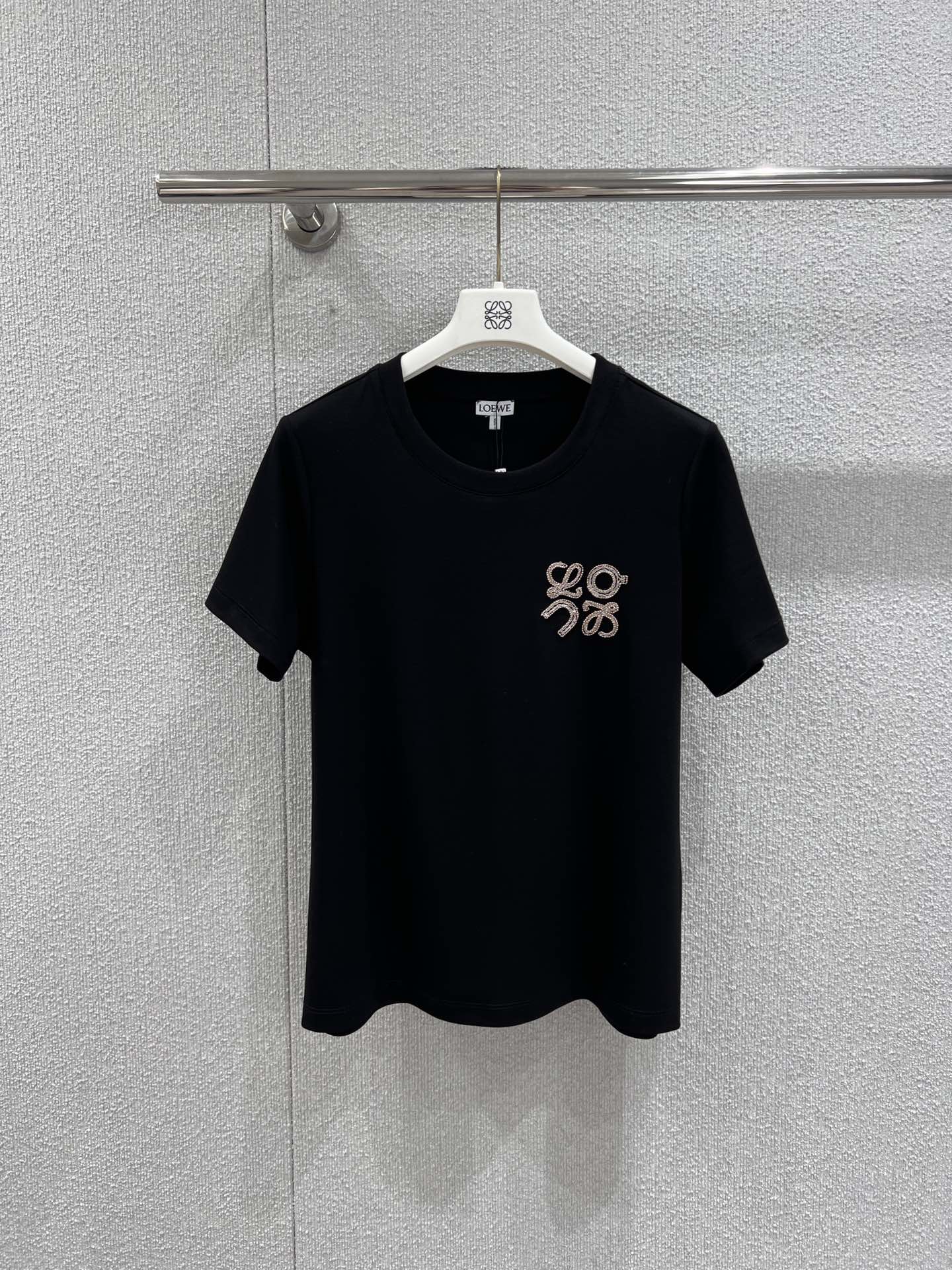 NO:710517,Support exchange Loew* 26Ss new early spring logo embroidered round neck short-sleeved T-shirt丨Exclusive high-end version!  Selected high-thread count pure cotton fabric, soft and delicate to the touch, yet stiff, close to the skin and breathable, perfect for early spring wear. The Anagram embroidery logo on the chest is the finishing touch of the design, using three-dimensional embroidery technology, the texture is full and three-dimensional, classic black and white, round neck cut to fit the neck line, slightly loose  The style is extremely tolerant to various body shapes. Whether worn alone to create a casual daily look, this T-shirt can become a versatile item in the early spring wardrobe with its low-key luxury. Ready for sale S/M/L real shot details, loewe, T-shirt, tees, t-shirt,19860909支持换款 Loew* 26Ss早春新款 logo刺绣圆领短袖T恤丨独家高版出品！精选高支数纯棉面料,触感柔软细腻且兼具挺括度,贴身穿戴亲肤透气,完美适配早春的穿着需求.胸前的Anagram刺绣标识是设计的点睛之笔,采用立体绣线工艺,纹理饱满立体,经典黑白两色,圆领剪裁贴合颈部线条,微宽松的版型对各种身形都有极好的包容度.无论是单穿打造随性的日常造型,这件T恤都能以低调的奢华感,成为早春衣橱里的百搭刚需单品.现货发售S/M/L实拍细节图,,loewe,T-shirt,tees，t-shirt,,Women's clothing