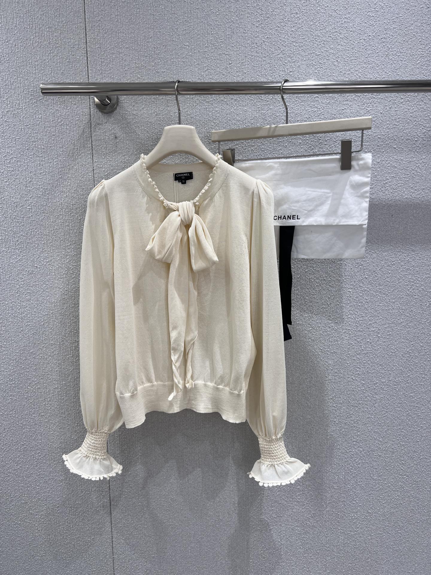 NO:710483,Supports model exchange Chane* 26C Advanced Handicraft Workshop Series New Lace Bow Knit Sweater丨Exclusively developed by yb!  Top quality production!  Selected off-white silk blend fabric, three-dimensional bow tie at the neckline to soften the lines, hand-crocheted lace on the neckline and cuffs, puff sleeves with gathered cuffs to create a retro French romance; ribbed waist design at the hem outlines the body shape, blending haute couture craftsmanship and elegant aesthetics into the details, which is the finishing touch to create a light and sophisticated style. Ready for sale S/M/L real shot details, chanel, real silk,19860909支持换款 Chane* 26C高级手工坊系列新款 花边蝴蝶结针织衫丨独家yb开发！顶级高版出品！甄选米白色真丝混纺面料,领口立体蝴蝶结系带柔化线条,领口与袖口缀以手工钩织花边,泡泡袖型搭配收褶袖口营造复古法式浪漫；下摆罗纹收腰设计勾勒身形,将高定手工技艺与优雅美学融于细节,是打造轻熟风造型的点睛之选.现货发售S/M/L实拍细节图,,chanel,real silk,,Women's clothing