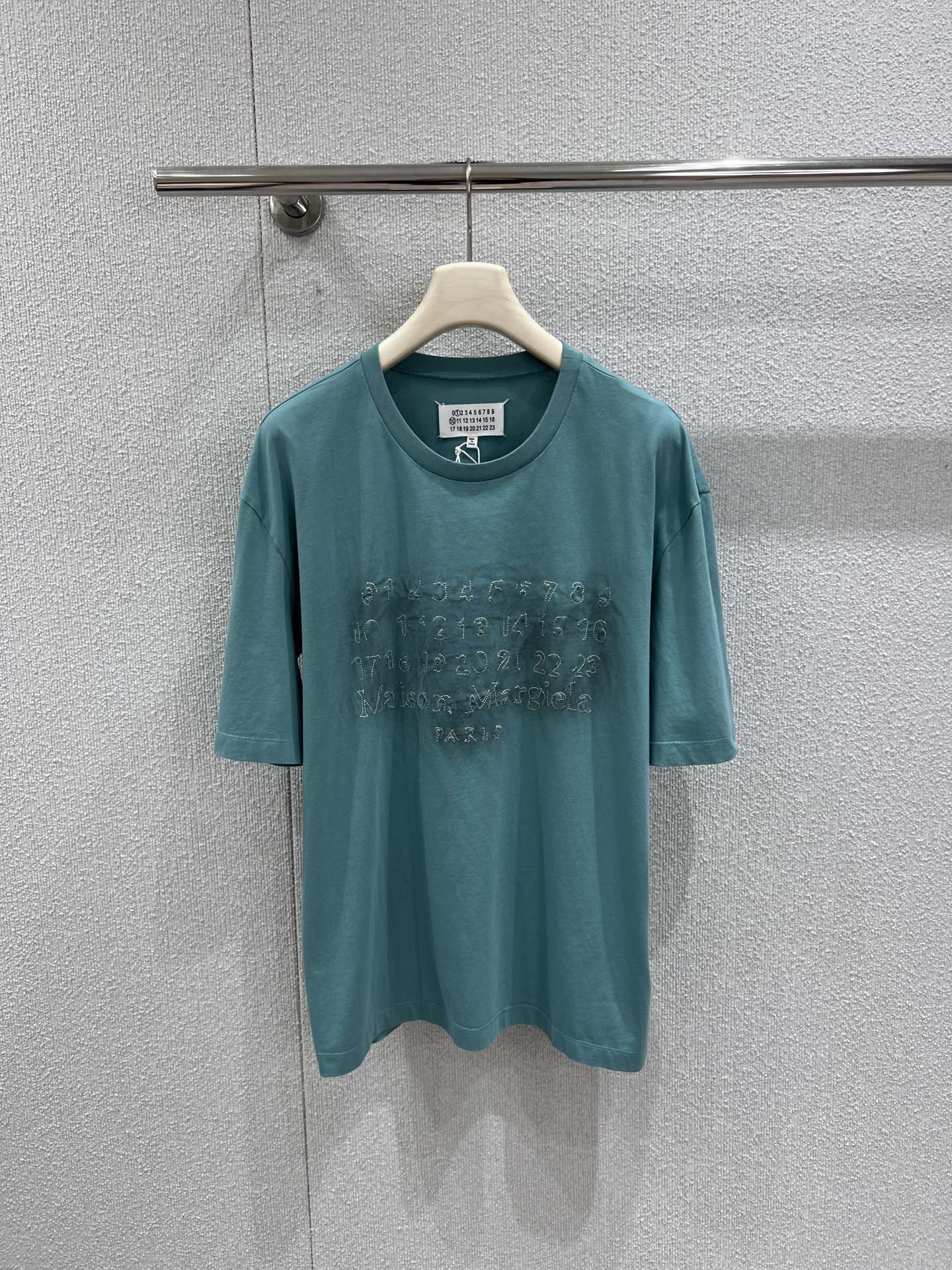 NO:713787,Support exchange of Maiso*n Margiel*a 26Ss spring and summer new digital stitching logo distressed short-sleeved T-shirt丨Exclusive high-end version!  The iconic digital code is sewn into this lake blue T-shirt. The distressed washing process allows the fabric to show natural retro wrinkles, and the loose oversize version creates an effortless sense of relaxation. It can be paired with white wide-leg pants or cycling pants to instantly look stunning. The number logo on the chest uses same-color stitching, which is low-key without losing details. The upper body has a casual and uninhibited street aura, making it an eye-catching must-have for fashionistas in spring and summer. Available now.  S/M/L real shot details, versace, T-shirt, tees, t-shirt,19860909支持换款Maiso*n Margiel*a 26Ss春夏新款 数字缝线徽标做旧短袖T恤丨独家高版出品！把标志性的数字密码缝进这件湖水蓝T恤里.做旧水洗工艺让面料呈现自然的复古褶皱,宽松Oversize版型营造出毫不费力的松弛感,搭配白色阔腿裤或骑行裤都能瞬间出片.胸前的数字徽标采用同色系缝线,低调又不失细节,上身自带随性不羁的街头气场,是潮人春夏出街的吸睛必备.现货发售 S/M/L实拍细节图,,versace,T-shirt,tees，t-shirt,,Women's clothing