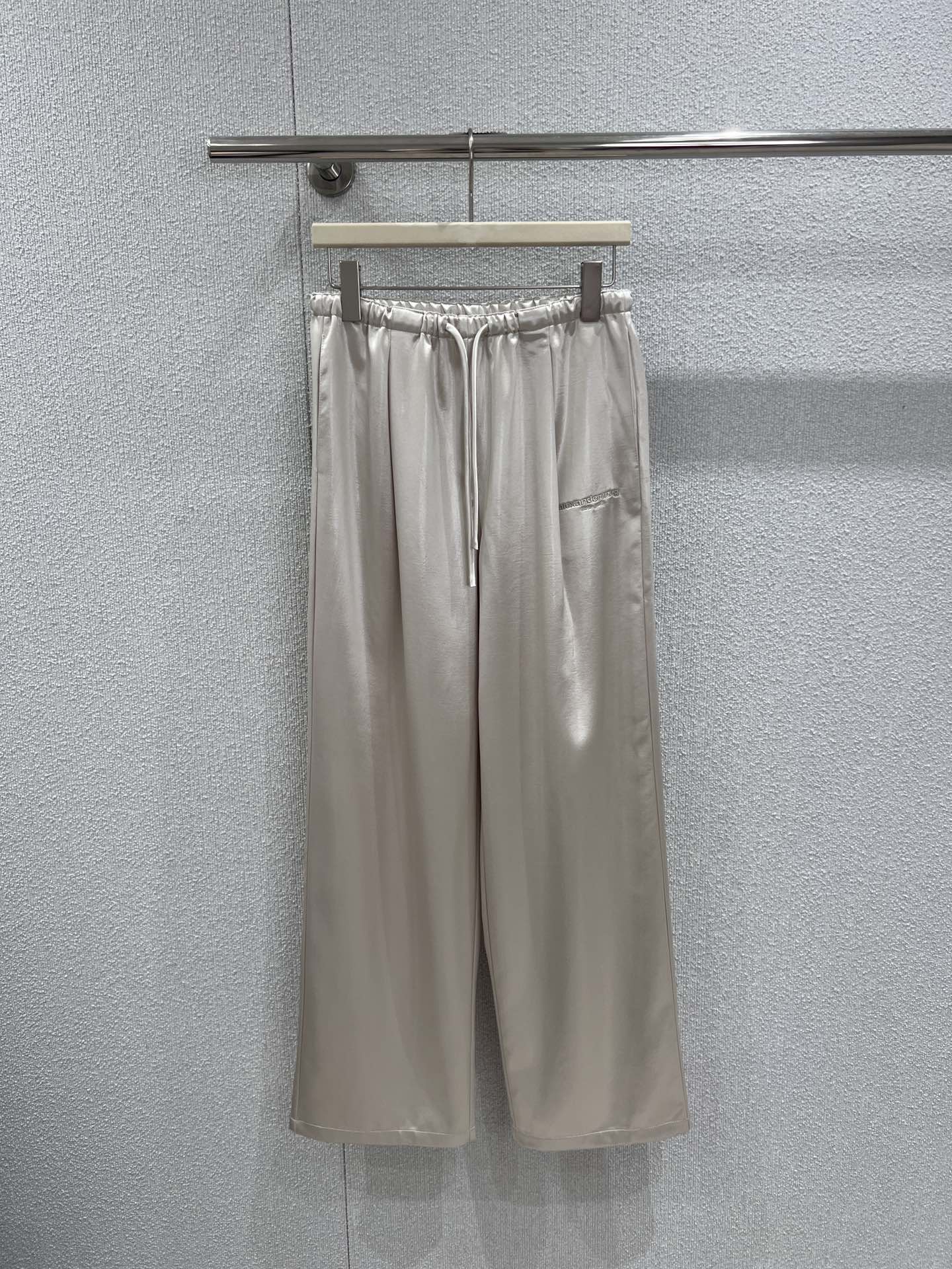 NO:716410,Supports exchange of Alexander* Wang 26Ss early spring new style letter embroidered imitation acetate casual trousers丨Exclusive high-end version!  Recreate the relaxed feeling on the street with liquid glossy fabric. The smooth drapey imitation acetic acid material has a high-end soft light. Champagne gold and metallic gray are available in two colors, suitable for different styles. The drawstring design at the waist combines comfort and style, and the micro letter embroidery on the side seam low-key highlights the logo. The wide  The loose and wide-leg version optimizes the body proportions. Whether it is paired with a short top to create a hot girl look that is 'tight up and loose at the bottom', or worn with a suit to create a commuting atmosphere, it can be the finishing touch of the early spring look. Ready-made S/M/L real shot details,,business  suit,19860909支持换款 Alexande* Wang 26Ss早春新款 字母刺绣仿醋酸休闲长裤丨独家高版出品！以液态光泽感面料重塑街头松弛感.垂坠顺滑的仿醋酸材质自带高级柔光,香槟金与金属灰双色可选,适配不同风格.腰头抽绳设计兼具舒适度与造型感,侧缝的微型字母刺绣低调彰显标识,宽松阔腿版型优化身形比例,无论是搭配短款上衣打造“上紧下松”的辣妹造型,还是外搭西装营造通勤氛围,都能成为早春造型的点睛之笔.现货发售S/M/L实拍细节图,,business suit,,Women's clothing