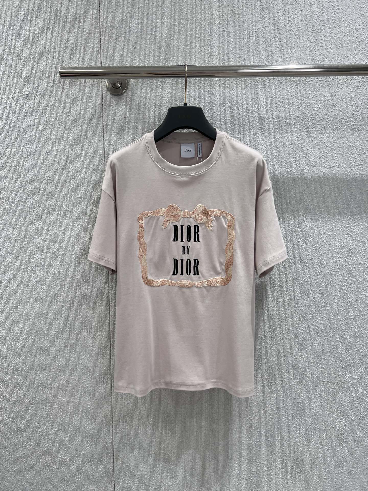 NO:716453,Support exchange Di*r 26Ss new early spring letter embroidered round neck short-sleeved T-shirt丨Exclusive high-end version!  The gentle background is outlined with low-saturated light nude pink, and the letter embroidery is paired with a light golden brown frame with lace texture, which cleverly combines French retro and modern sophistication. The high-count cotton fabric is soft and breathable, and the loose-shouldered version is lazy and casual. It can be paired with jeans to create a relaxed feeling for daily use.  It can also be combined with a satin skirt to create an elegant commuting look. It is a versatile choice to enhance your temperament in the early spring wardrobe. Available now, S/M/L, real shot details, skirts, jeans, T-shirts, tees, t-shirts,19860909支持换款Di*r 26Ss早春新款 字母刺绣圆领短袖T恤丨独家高版出品！以低饱和浅裸粉勾勒温柔底色,字母刺绣搭配蕾丝质感的浅金棕边框,将法式复古与现代精致巧妙融合.高支棉面料软糯透气,宽松落肩版型慵懒随性,既能搭配牛仔裤打造松弛感日常,也能与缎面半裙组合出优雅通勤造型,是早春衣橱里提升气质的百搭之选.现货发售S/M/L实拍细节图,,skirts,jeans,T-shirt,tees，t-shirt,,Women's clothing