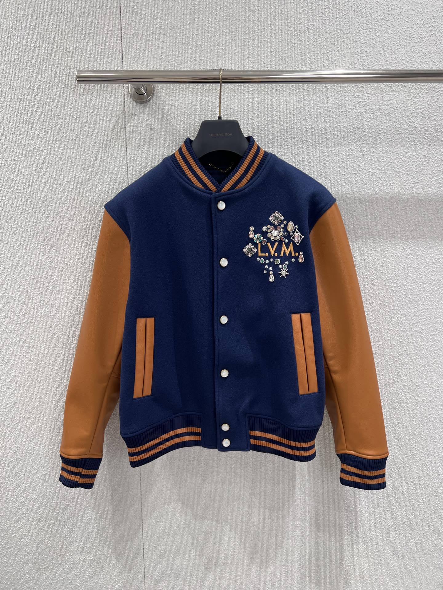 NO:716471,Support exchange Louis Vuitt*n 26SS new early spring beaded embroidered baseball jacket | Exclusive high-end version!  The warm brown lambskin sleeves are spliced with dark navy wool blend fabric, and the retro contrasting color combines texture and layering. The 'L.V.M.' letters on the chest are surrounded by bright beading and crystal embroidery, and the details are gorgeous and eye-catching; the logo and birth year are three-dimensionally embroidered on the back, highlighting the collection-level craftsmanship. Loose silhouette  The ribbed collar and cuffs have both warmth and retro sportiness. They can be worn with jeans to create a relaxed feeling on the street, or worn with a sweater for elegant commuting. It is a luxury item that is both recognizable and practical in the early spring wardrobe. Available now in S/M/L, real shot details, louis  vuitton,jeans,jackets & coats,jackets & coats,sheepskin,19860909支持换款 Louis Vuitt*n 26SS早春新款 钉珠刺绣棒球夹克外套丨独家高版出品！以深藏青羊毛混纺面料拼接暖棕小羊皮袖身,复古撞色兼具质感与层次.胸前“L.V.M.”字母被满幅璀璨钉珠与水晶刺绣簇拥,细节华丽吸睛；后背立体刺绣的标识与诞生年份,彰显典藏级工艺.宽松廓形不挑身形,罗纹领与袖口兼具保暖性与复古运动感,既能搭配牛仔裤打造街头松弛感,也能内搭针织衫诠释优雅通勤,是早春衣橱里兼具辨识度与实穿性的奢潮单品.现货发售S/M/L实拍细节图,,louis vuitton,jeans,jackets & coats,jackets & coats,sheepskin,,Women's clothing