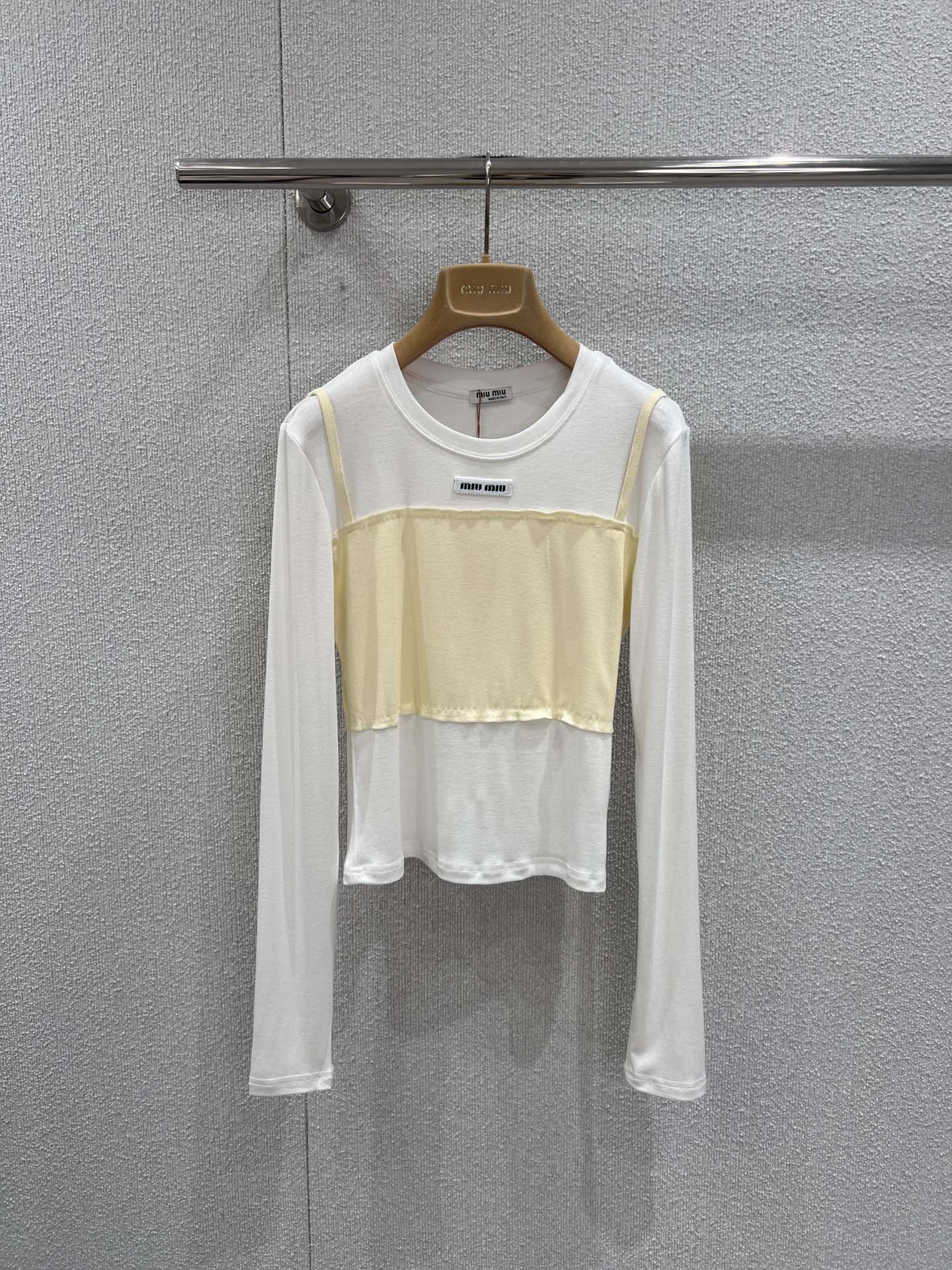 NO:730801,Support exchange Miumi* 26Ss early spring new style micro-label fake two-piece long-sleeved T-shirt bottoming shirt丨Exclusive high-end version!  Minimalist splicing techniques are used to create a sense of layering. The skin-friendly white base is paired with contrasting bandeau-style stacking pieces to create a casual yet exquisite layering effect. The micro-logo on the neckline is low-key for recognition, the soft and drapey fabric fits the body shape, and the right short cut can optimize the body proportions.  Whether worn alone inside or outside with a suit, it can be easily adapted to various scenarios such as commuting, dating, etc. It is a rare and versatile foundation for early spring wardrobes. Ready-made S/M/L real shot details,, miumiu, tees, t-shirt, business  suit,19860909支持换款 Miumi* 26Ss早春新款 微标假两件长袖T恤打底衫丨独家高版出品！以极简拼接手法打造层次感.亲肤的白色基底搭配撞色抹胸式叠片,营造出随性又精致的叠穿效果.领口处的微型Logo低调彰显辨识度,柔软垂坠的面料贴合身形,恰到好处的短款剪裁能优化身材比例.无论是单穿内搭还是外搭西装,都能轻松适配通勤、约会等多种场景,是早春衣橱里不可多得的百搭打底.现货发售S/M/L实拍细节图,,miumiu,tees，t-shirt,business suit,,Women's clothing