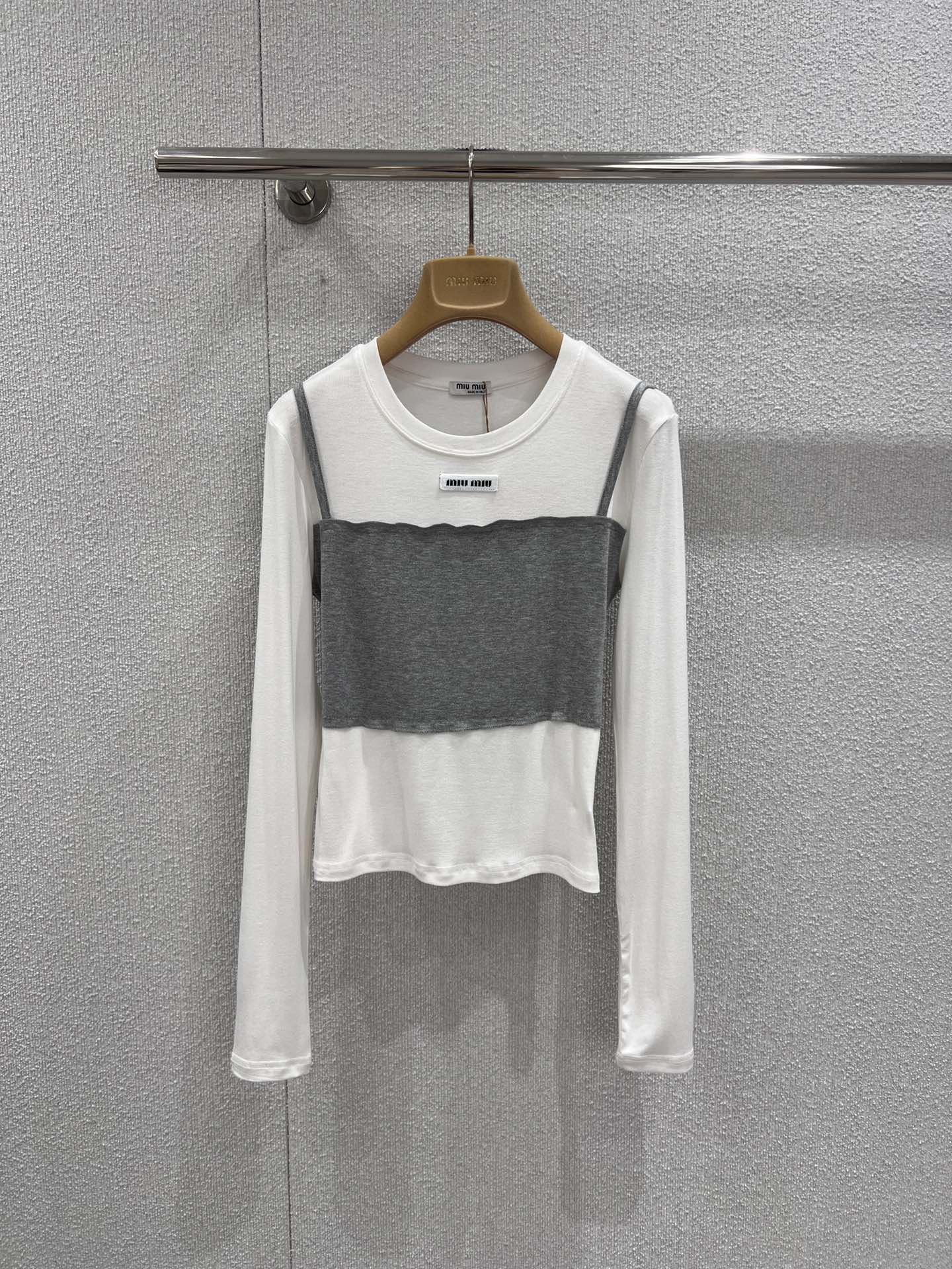 NO:730763,Support exchange Miumi* 26Ss early spring new style micro-label fake two-piece long-sleeved T-shirt bottoming shirt丨Exclusive high-end version!  Minimalist splicing techniques are used to create a sense of layering. The skin-friendly white base is paired with contrasting bandeau-style stacking pieces to create a casual yet exquisite layering effect. The micro-logo on the neckline is low-key for recognition, the soft and drapey fabric fits the body shape, and the right short cut can optimize the body proportions.  Whether worn alone inside or outside with a suit, it can be easily adapted to various scenarios such as commuting, dating, etc. It is a rare and versatile foundation for early spring wardrobes. Ready-made S/M/L real shot details,, miumiu, tees, t-shirt, business  suit,19860909支持换款 Miumi* 26Ss早春新款 微标假两件长袖T恤打底衫丨独家高版出品！以极简拼接手法打造层次感.亲肤的白色基底搭配撞色抹胸式叠片,营造出随性又精致的叠穿效果.领口处的微型Logo低调彰显辨识度,柔软垂坠的面料贴合身形,恰到好处的短款剪裁能优化身材比例.无论是单穿内搭还是外搭西装,都能轻松适配通勤、约会等多种场景,是早春衣橱里不可多得的百搭打底.现货发售S/M/L实拍细节图,,miumiu,tees，t-shirt,business suit,,Women's clothing