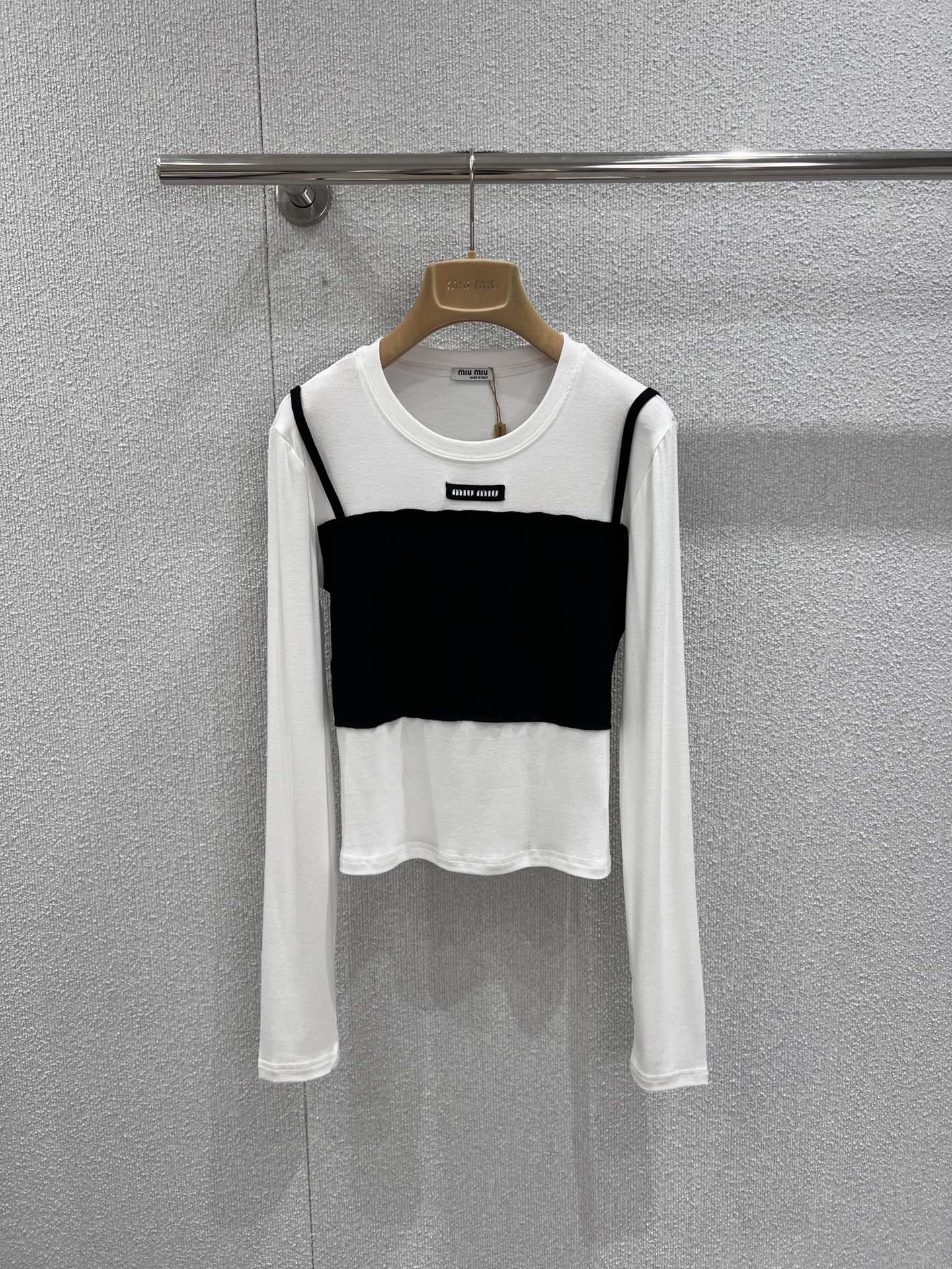 NO:730815,Support exchange Miumi* 26Ss early spring new style micro-label fake two-piece long-sleeved T-shirt bottoming shirt丨Exclusive high-end version!  Minimalist splicing techniques are used to create a sense of layering. The skin-friendly white base is paired with contrasting bandeau-style stacking pieces to create a casual yet exquisite layering effect. The micro-logo on the neckline is low-key for recognition, the soft and drapey fabric fits the body shape, and the right short cut can optimize the body proportions.  Whether worn alone inside or outside with a suit, it can be easily adapted to various scenarios such as commuting, dating, etc. It is a rare and versatile foundation for early spring wardrobes. Ready-made S/M/L real shot details,, miumiu, tees, t-shirt, business  suit,19860909支持换款 Miumi* 26Ss早春新款 微标假两件长袖T恤打底衫丨独家高版出品！以极简拼接手法打造层次感.亲肤的白色基底搭配撞色抹胸式叠片,营造出随性又精致的叠穿效果.领口处的微型Logo低调彰显辨识度,柔软垂坠的面料贴合身形,恰到好处的短款剪裁能优化身材比例.无论是单穿内搭还是外搭西装,都能轻松适配通勤、约会等多种场景,是早春衣橱里不可多得的百搭打底.现货发售S/M/L实拍细节图,,miumiu,tees，t-shirt,business suit,,Women's clothing