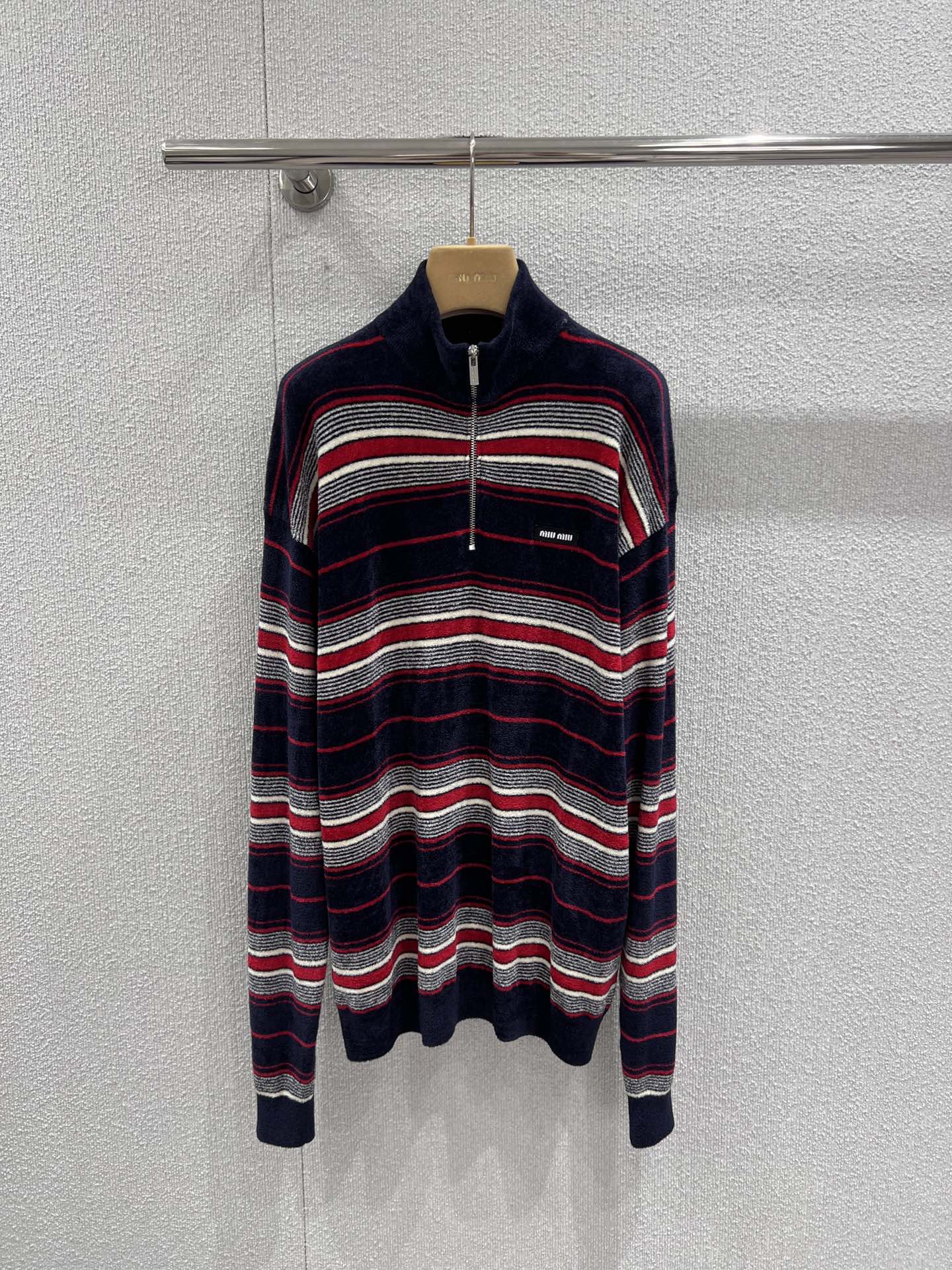 NO:731639,Support exchange MiuM*u 26Ss new early spring flannel half-zip striped sweater丨exclusively developed by yb!  High quality production!  It is based on delicate and soft flannel, with retro stripes intertwined in red, white and navy blue, conveying a lazy and casual girlish feel in the soft luster. The half-zip high collar design has both warmth and style, and the opening and closing of the neckline can be freely adjusted; the loose shoulder cut is suitable for various body shapes, and the mini logo on the chest low-key highlights the identity. Regardless of  Whether paired with a pleated skirt to create a college sweet girl style, or combined with a leather skirt and boots to create a cool atmosphere, it can become a core item for early spring layering. It is a wardrobe must-have with both retro charm and practicality. Ready-made S/M/L real shot details,,miumiu,boots,skirts,sweaters,19860909支持换款 MiuM*u 26Ss早春新款 法兰绒半拉链条纹毛衣丨独家yb开发！高版出品！以细腻软糯的法兰绒为基底,融入红、白、藏青三色交织的复古条纹,在柔和光泽中传递出慵懒随性的少女感.半拉链高领设计兼具保暖性与造型感,可自由调节领口开合度；宽松落肩剪裁适配多元身形,胸前的迷你徽标低调彰显身份.无论是搭配百褶裙打造学院甜妹风,还是与皮裙、长靴组合营造酷飒氛围,都能成为早春叠穿的核心单品,是兼具复古韵味与实穿性的衣橱必备.现货发售S/M/L实拍细节图,,miumiu,boots,skirts,sweaters,,Women's clothing