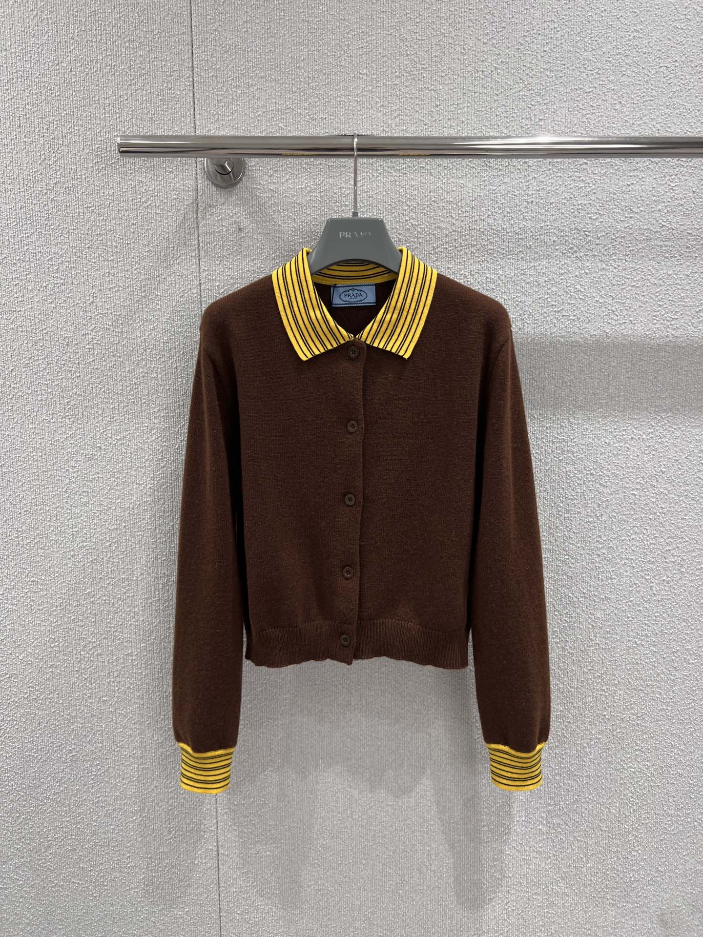NO:734193,Supports exchange. Prad* 26Ss early spring new style contrasting lapel knitted cardigan丨Exclusive high-end version!  It is made of warm and rich caramel brown wool blended fabric, which feels soft and waxy and dense, and has skin-friendly and warm properties. The collar and cuffs are spliced with yellow and black striped ribs, and the retro college-style design echoes the fashion trends of the season and visually brightens the overall look. The neat short cut is paired with a delicate button placket to optimize body proportions.  Showing casual elegance. The back is decorated with a triangle logo in a low-key manner, and the details highlight the luxurious gene. Whether worn with a suspender skirt to create a sweet and cool style, or paired with jeans to create a relaxed feel, it can be the finishing touch of the look. Ready-made S/M/L real shot details, prada, skirts, jeans,19860909支持换款 Prad* 26Ss早春新款 撞色翻领针织开衫丨独家高版出品！以温暖浓郁的焦糖棕羊毛混纺面料为主体,触感软糯绒密,自带亲肤保暖属性.领口与袖口拼接黄黑条纹罗纹,复古学院风设计呼应当季流行趋势,视觉上点亮整体造型.利落短款剪裁搭配精致纽扣门襟,优化身材比例的同时尽显随性优雅.后背低调点缀三角徽标,细节处彰显奢华基因,无论是内搭吊带裙打造甜酷风,还是配牛仔裤营造松弛感,都能成为造型点睛之笔.现货发售S/M/L实拍细节图,,prada,skirts,jeans,,Women's clothing