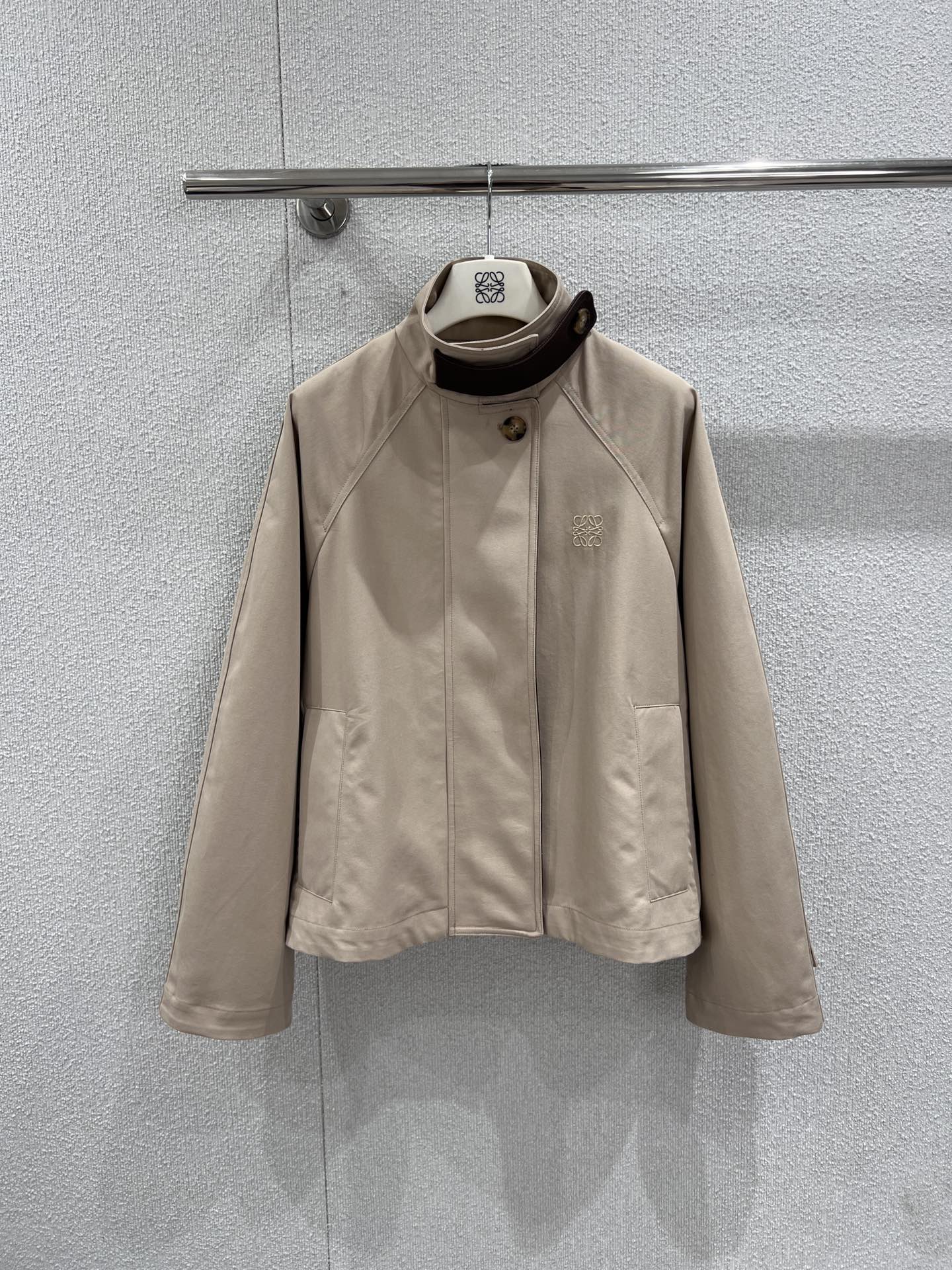 NO:734185,Supports exchange Loew* 26Ss early spring new style logo embroidered short windbreaker jacket丨Exclusively developed by yb!  Top quality production!  Made of light khaki high-density cotton fabric, it has both a crisp texture and a soft drape. The stand-up collar is spliced with dark brown leather details and embellished with retro round buttons, echoing the ingenuity. The Anagram logo is low-key embossed on the left side of the body, and the shawl-style structure and drop sleeves are on the back.  The shape gives the loose silhouette a layered aesthetic. The ribbed cuffs and hidden zipper design take into account windproof practicality and minimalist aesthetics. It is a highly suitable item for spring commuting and city roaming. Ready-made S/M/L real shot details,,loewe,jackets  & coats,shawls,19860909支持换款 Loew* 26Ss早春新款 徽标刺绣短款风衣外套丨独家yb开发！顶级高版出品！以浅卡其色高密棉质面料打造,兼具挺括质感与柔和垂坠感.立领处拼接深棕色皮革细节,点缀复古圆形纽扣,呼应匠心底蕴.衣身左侧低调压印Anagram徽标,后背的披肩式结构与落肩袖型,赋予宽松廓形以层次美感.罗纹袖口与隐藏式拉链设计,兼顾防风实用性与极简美学,是春日通勤与城市漫游的高适配单品.现货发售S/M/L实拍细节图,,loewe,jackets & coats,shawls,,Women's clothing