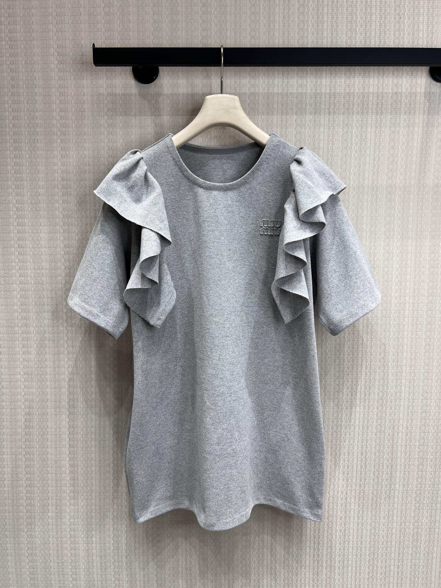 NO:804765,26 spring and summer new products Miu’s gray tones are really amazing. This ruffled short-sleeved piece directly welds the sense of relaxation and girliness to the body!  Classic heather gray base, gentle and high-end, showing great whitening!  The most amazing thing is the asymmetric ruffle sleeves!  The layers fluttering in the wind perfectly cover the body. Sisters with thick arms can just rush in with their eyes closed!  The exquisite Miu embroidery logo on the chest is the finishing touch, and it is low-key and luxurious. From a distance, it does not look like a street product. It comes with a light luxury filter. Ready for sale, smL real shot details,, miumiu, T-shirt,1986090926春夏新品 Miu家的灰色调真的绝了这件荷叶边短袖直接把松弛感和少女感焊在身上了！经典麻灰色基底,温柔又高级,巨显白！ 最绝的是不对称荷叶边袖子！随风飘动的层次感,完美遮住拜拜肉,手臂粗的姐妹直接闭眼冲！胸口精致的Miu刺绣Logo点睛,低调中透着奢华,远远看去就不是街边货,自带轻奢滤镜.现货出售 smL实拍细节图,,miumiu,T-shirt,,Women's clothing