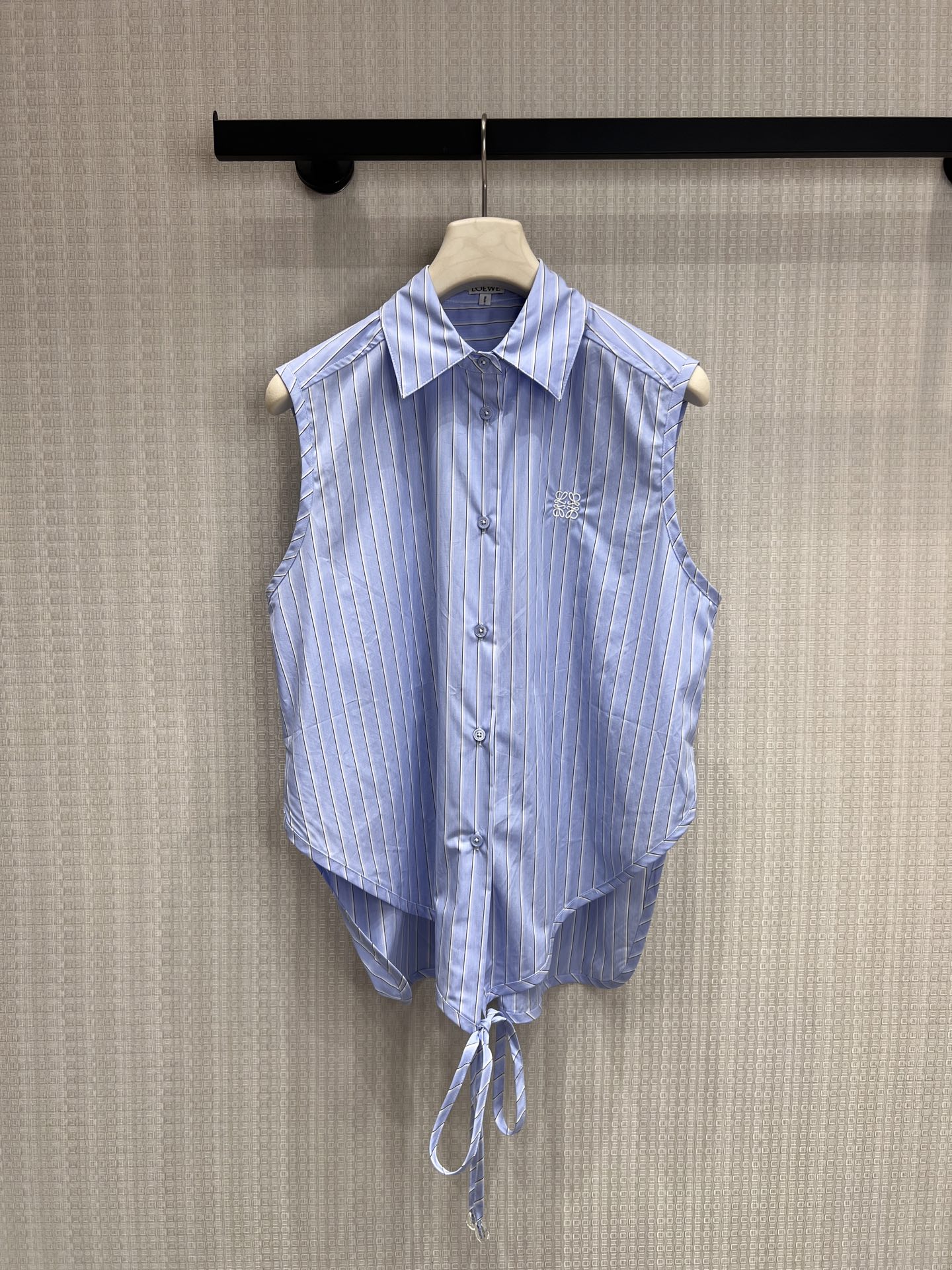 NO:865232,High version 26 spring and summer new arrival Loe ** striped sleeveless strappy shirt. Classic blue and white vertical stripes bring a refreshing academic feel, and the brand embroidery logo is hidden on the body. The asymmetrical cut is short in the front and long in the back, and the hem tie + pom-pom detail combines design and playfulness. The drapey fabric is breathable and skin-friendly, and the sleeveless cut neatly highlights the shoulder and neck lines. It can be easily used for commuting and leisure. Ready for sale smL,, loewe, shirts,19860909高版本 26春夏新品 Loe **条纹无袖绑带衬衫 经典蓝白竖条纹自带清爽学院感,衣身暗藏品牌刺绣标识 前短后长的不对称剪裁,下摆系带+毛球细节,兼具设计感与俏皮感 垂坠感面料透气亲肤,无袖剪裁利落显肩颈线条,通勤、休闲都能轻松驾驭现货出售smL,,loewe,shirts,,Women's clothing