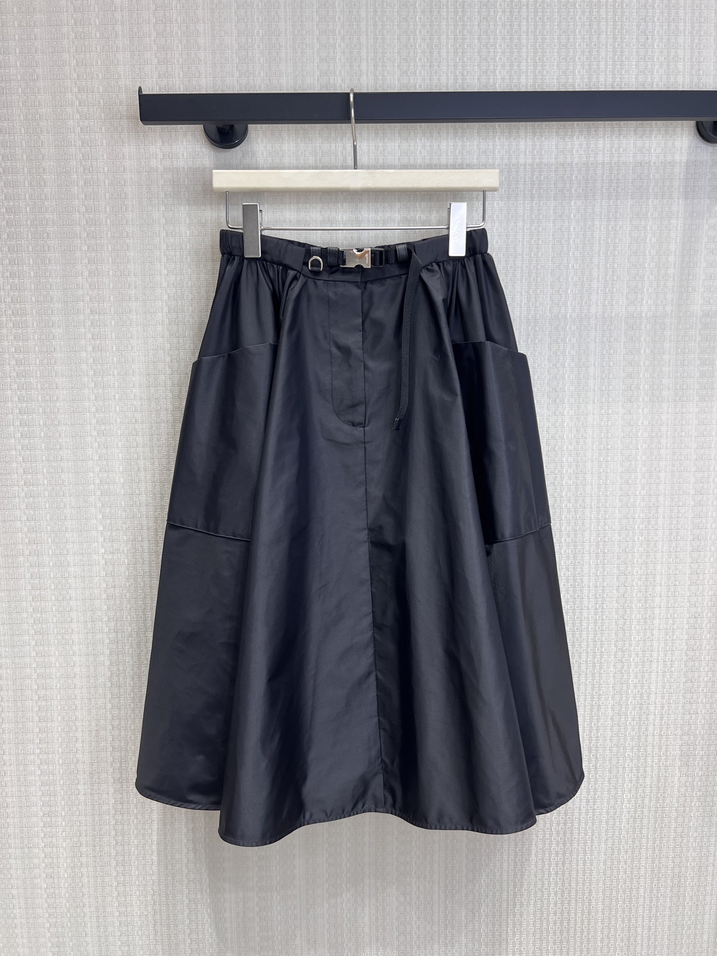 NO:840149,26 spring and summer new product Pra**'s iconic regenerated nylon fabric has a matte high-end texture, is stiff and anti-wrinkle, and is draped and stylish. The soft pleats create a three-dimensional umbrella shape, with functional belt and metal buckle details. It combines elegant feminine lines with practical workwear attributes. The large pockets on both sides are designed to take into account both style and practicality. The mid-length A-line version perfectly modifies the waist and hip lines, hides the flesh and makes you look slimmer, and is suitable for many styles. Ready for sale smL, prada,1986090926春夏新品 Pra**标志性再生尼龙面料,自带哑光高级质感,挺括抗皱,垂坠有型. 柔和褶皱打造立体伞状廓形,搭配机能风腰带与金属扣细节, 兼具优雅女性化线条与实用工装属性,两侧大口袋设计兼顾造型与实用性, 中长A字版型完美修饰腰臀线条,藏肉显瘦,适配多风格搭配.现货出售smL,,prada,,Women's clothing