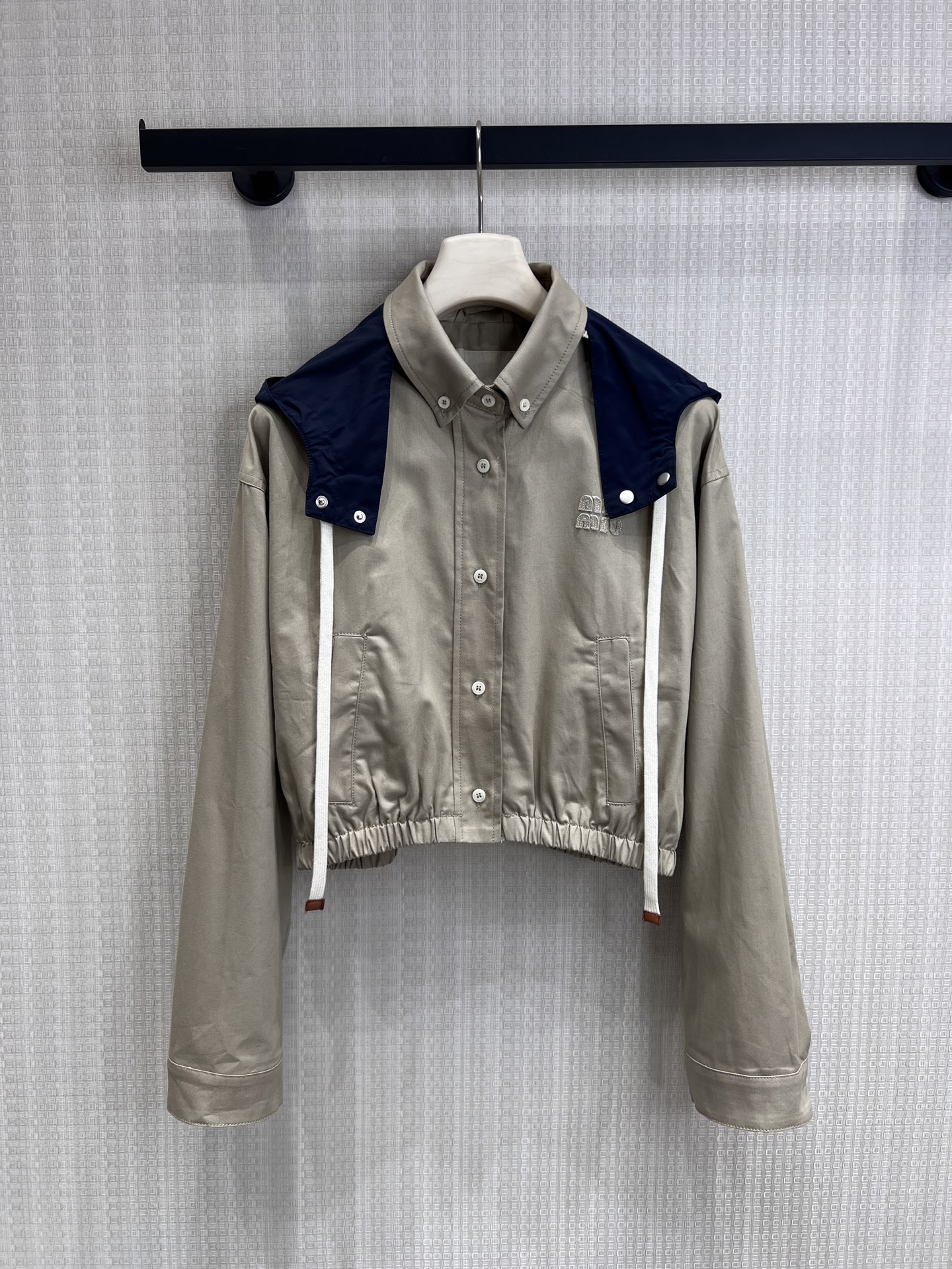 NO:840193,26 spring and summer new product Miu limited-edition contrast-color hooded short work jacket, iconic college-style aesthetics, khaki work fabric with navy blue contrast detachable hood, exquisite embroidered logo on the chest to highlight the brand recognition. The elastic design of the short hem optimizes body proportions, and the loose shoulder version is suitable for multiple body shapes. It combines the neatness of work clothes with the sweetness of a girl. It can be worn alone or layered to create a retro college look. Ready for sale smL,, miumiu, jackets &  coats, hats,1986090926春夏新品 Miu 限定撞色连帽短款工装外套, 标志性学院风美学,卡其色工装面料搭配藏蓝撞色可拆卸连帽,胸前精致刺绣Logo彰显品牌辨识度.短款下摆松紧设计优化身材比例,宽松落肩版型适配多元身形,兼具工装的利落与少女的甜酷,单穿叠搭皆可打造复古学院造型.现货出售smL,,miumiu,jackets & coats,hats,,Women's clothing