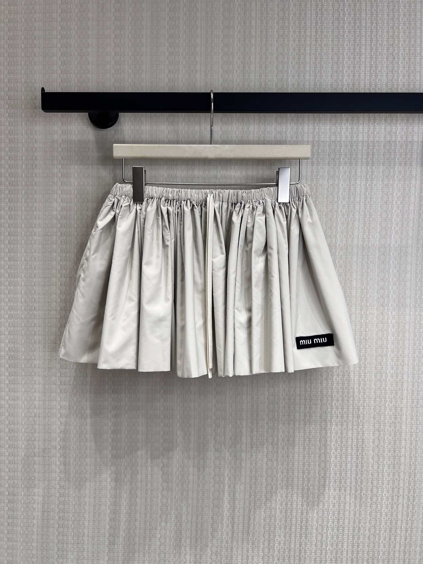NO:840181,26 spring and summer new product Miu** off-white fluffy drawstring skirt with cool girl aesthetics, made of matte off-white fabric, elastic waist with drawstring design, creating a fluffy A-line skirt, with an age-reducing college atmosphere. The brand woven label on the side low-key highlights the identity, is both playful and girly, and can be matched with the same series of work jackets to easily unlock the Italian sweet and cool look. Ready for sale smL,, miumiu, skirts, jackets & coats,1986090926春夏新品 Miu**米白蓬感抽绳半裙 酷少女美学,以哑光米白面料打造,松紧腰头搭配抽绳设计,打造蓬松A字裙摆,自带减龄学院氛围.侧边品牌织标低调彰显身份,兼具俏皮与少女感,可与同系列工装外套搭配成套,轻松解锁意式甜酷造型.现货出售smL,,miumiu,skirts,jackets & coats,,Women's clothing