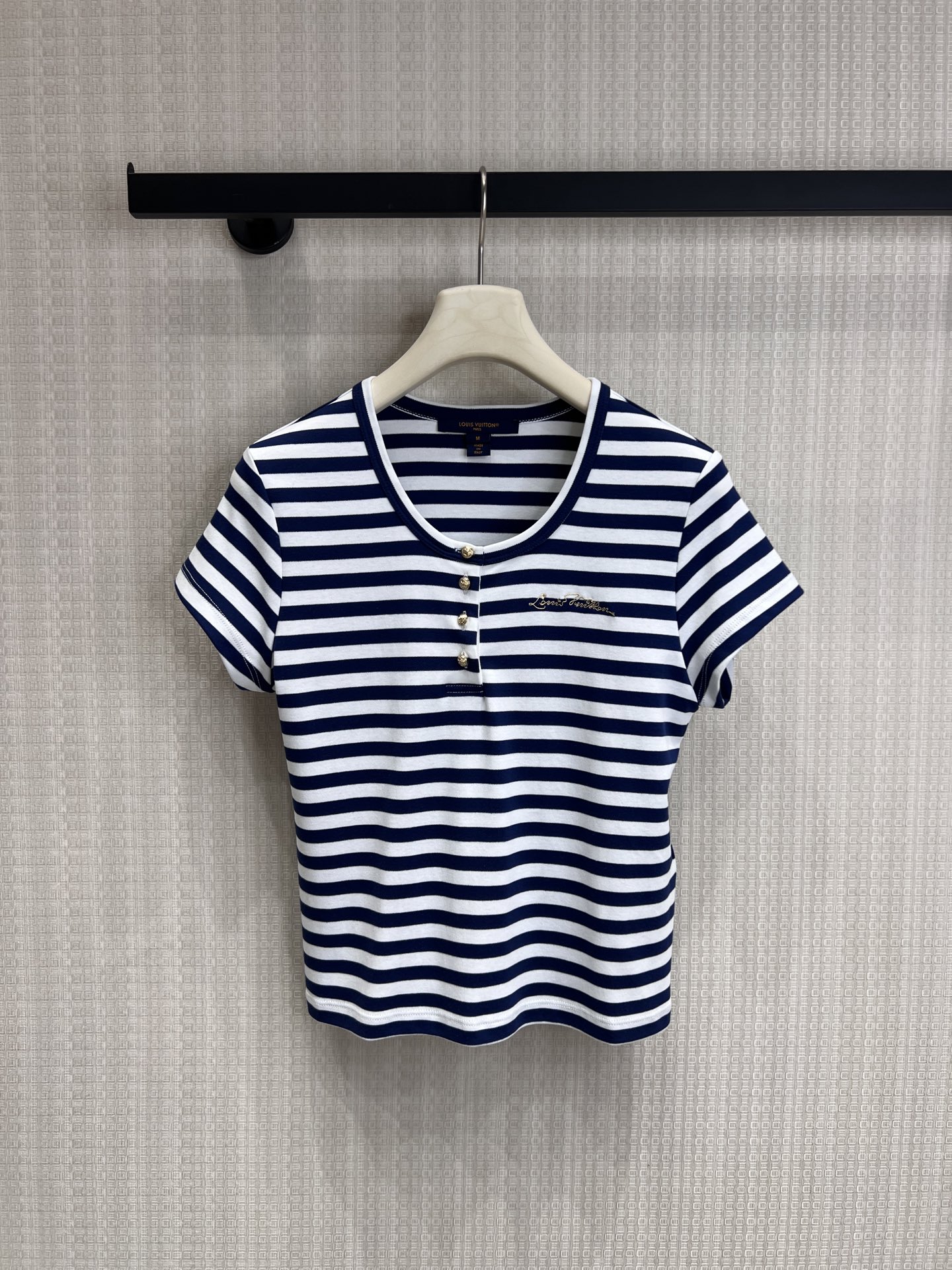 NO:840187,26 spring and summer new product Lou**Vui** limited edition blue and white striped Henley collar striped short-sleeved T-shirt. Inheriting LV's iconic nautical aesthetics, the classic blue and white stripes reproduce the French holiday style. The Henry collar is matched with metal buttons, and the exquisite embroidered logo on the chest low-key highlights the brand identity. The slim and short version optimizes body proportions. The soft knitted fabric combines comfort and texture. Wear it alone to create a relaxed French style. Layer a jacket to unlock a variety of outfits. Ready for sale smL, louis  vuitton,jackets & coats,T-shirt,tees,t-shirt,1986090926春夏新品 Lou**Vui**限定蓝白条纹亨利领条纹短袖T恤 承袭LV标志性航海美学,经典蓝白条纹复刻法式度假风情.亨利领搭配金属纽扣,胸口精致刺绣Logo低调彰显品牌身份,修身短款版型优化身材比例,柔软针织面料兼顾舒适与质感,单穿打造松弛法式造型,叠搭外套亦可解锁多元穿搭.现货出售smL,,louis vuitton,jackets & coats,T-shirt,tees，t-shirt,,Women's clothing