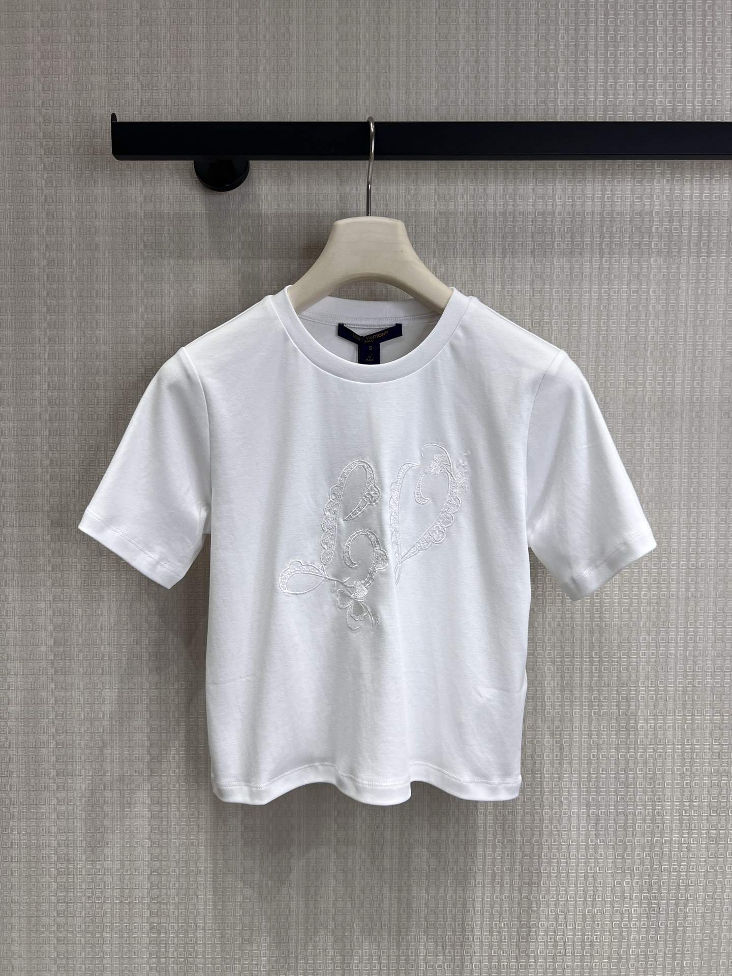 NO:841527,26 spring and summer new product LouisV** embroidered short white T. Luxury brand details in minimalism. Reject monotony and use details to define high-end. Customized luxury brand homologous fabrics, soft and skin-friendly, full of breathability, and comfortable wrapping on the upper body. The hand-made embroidery technology on the chest is inspired by the brand's iconic elements, paired with lace lines, exquisite and unobtrusive, saying goodbye to the sameness of ordinary white T-shirts.  Fitted and short, it modifies the body shape, easily creates superior proportions, and is friendly to all body types. Ready for sale smL,, louis vuitton,1986090926春夏新品 LouisV**刺绣短款白T 极简中的奢牌细节 拒绝单调,用细节定义高级感. 定制奢牌同源面料,触感软糯亲肤,透气度拉满,上身自带舒适包裹感. 胸口手工感刺绣工艺,以品牌标志性元素为灵感,搭配蕾丝花边线条,精致又不张扬,告别普通白T的千篇一律. 合身短款版型,修饰身形,轻松打造优越比例,对各种身材都很友好.现货出售smL,,louis vuitton,,Women's clothing