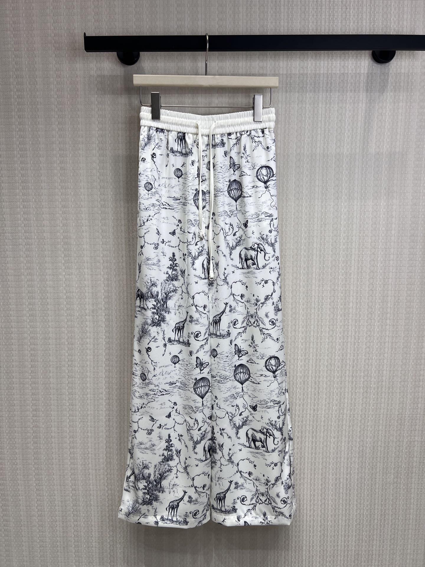 NO:844015,26 spring and summer new products original designer  The milky white background blends out the secret jungle with the texture of ink, and the prints of giraffes, elephants and hot air balloons are like a flowing French illustration, bringing a lazy and noble vacation atmosphere. The satin fabric with perfect drape makes the upper body cool and silky when walking.  It comes with a soft light filter; the elastic drawstring waistband is not flattering on your figure, and the wide-leg version can easily hide the fat on your waist, abdomen and legs. Pair it with a suspender belt or a white T-shirt, and it will create an atmospheric blockbuster with just a snap, ensuring your relaxed and fashionable look all summer. Ready for sale smL,,1986090926春夏新品 原创设计师 奶白底色晕染出水墨质感的丛林秘境,长颈鹿、大象与热气球的印花像一幅流动的法式插画,自带慵懒又贵气的度假氛围.垂坠感满分的缎面面料,上身凉丝丝的,行走间自带柔光滤镜；松紧抽绳腰头不挑身材,阔腿版型轻松藏住腰腹与腿部赘肉,搭配吊带或白T,随手一拍都是氛围感大片,承包你整个夏天的松弛时髦.现货出售smL,,,Women's clothing
