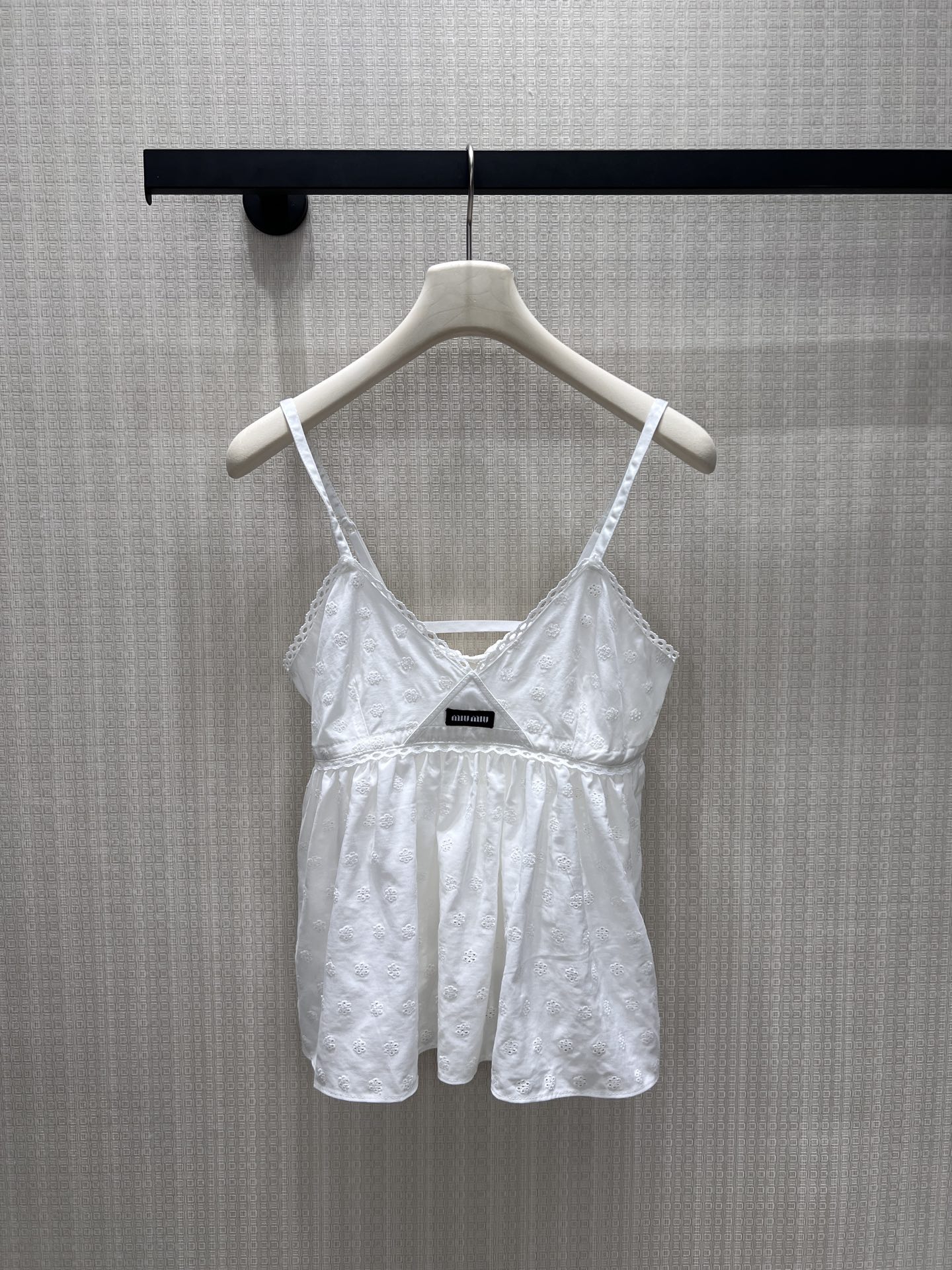 NO:863216,26 spring and summer new products Miu** style hollow embroidered sling, using pure white tones to outline the romance of girls. The V-neck is matched with lace, gently modifying the neck line; the waist is cut with an umbrella hem, which hides the body and makes you look slimmer while bringing a smart and fairy spirit. The full-frame embroidery texture is delicate, and the brand woven label is a low-key finishing touch. It is suitable for wearing alone or as an inner layer, and can easily unlock the exquisite and high-end sense of retro college style. Ready for sale smL,,miumiu,1986090926春夏新品 Miu**风镂空刺绣吊带,以纯净白调勾勒少女浪漫.V领搭配蕾丝花边,温柔修饰颈部线条；收腰伞摆剪裁,藏肉显瘦又自带灵动仙气.全幅刺绣肌理细腻,品牌织标低调点睛,单穿或内搭都适配,轻松解锁复古学院风的精致高级感.现货出售smL,,miumiu,,Women's clothing