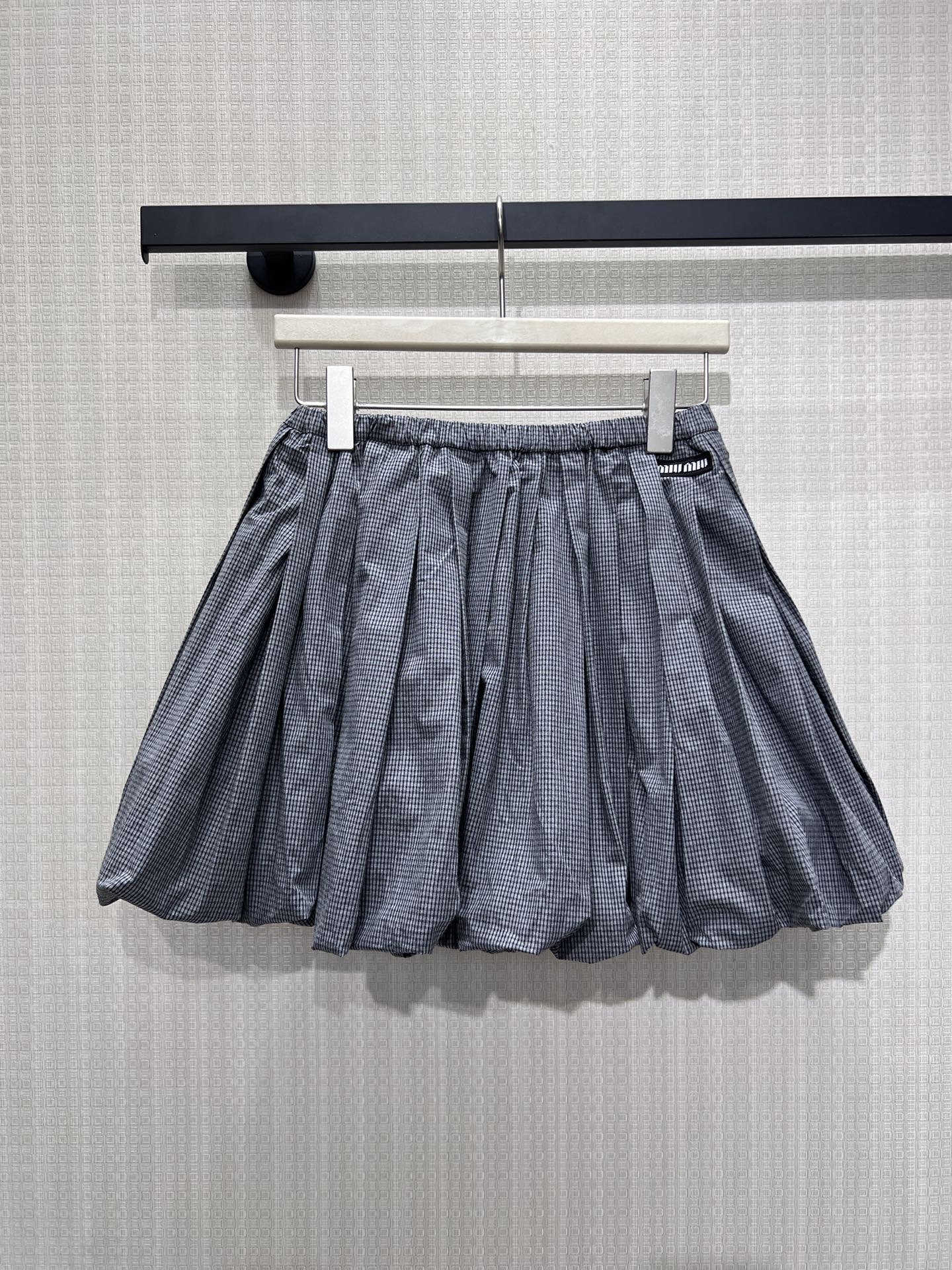 NO:870858,26 spring and summer new products  Miu** plaid bud skirt evokes memories of college style with gray-toned houndstooth. The neat pleats support the fluffy silhouette, the soft puffy hem has a playful atmosphere, and the brand logo on the waist is a low-key finishing touch. The high-waist cut optimizes the proportions, and the cotton-feel fabric is both stiff and comfortable  Suitable and easy to wear with a sweet and cool girly look, suitable for T-shirts and shirts, it is a versatile item in the wardrobe with its own age-reducing filter. Ready for sale smL, miumiu, skirts, shirts, tees, t-shirt,1986090926春夏新品 Miu**格纹花苞半裙,以灰调千鸟格唤醒学院风记忆.利落褶裥撑起蓬松廓形,软蓬下摆自带俏皮氛围,腰侧品牌标识低调点睛.高腰剪裁优化比例,棉感面料兼具挺括与舒适,轻松穿出甜酷少女感,适配T恤与衬衫,是衣柜里自带减龄滤镜的百搭单品.现货出售smL,,miumiu,skirts,shirts,tees，t-shirt,,Women's clothing