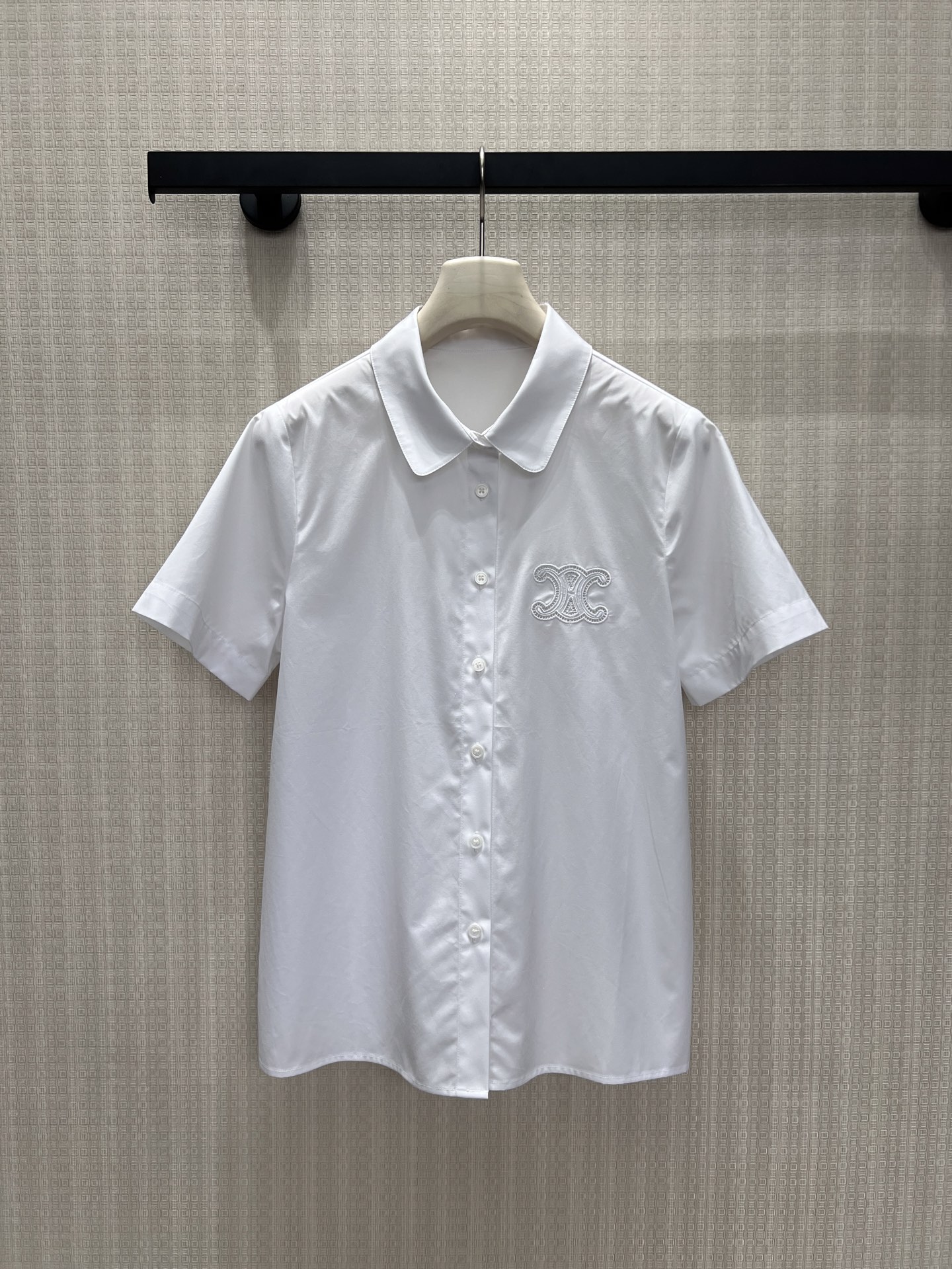 NO:873070,26 new spring and summer short-sleeved shirts  Cel** interprets the elegant core of the shirt with neat tailoring. The pure white fabric has a delicate luster, is skin-friendly and breathable. The small lapel and single-breasted design are clean and neat, and the embroidery on the chest outlines the brand logo with low-key lines, which is unobtrusive but highly recognizable. The silhouette is relaxed and moderate, and the upper body has a cool texture. It is a versatile style that can be easily adapted to the workplace and daily life, quietly showing high-end taste. Ready for sale smL, shirts, T-shirt,1986090926春夏新品短袖衬衫 Cel**以利落剪裁诠释衬衫的优雅内核,净白面料带着细腻光泽,亲肤透气.小翻领与单排扣设计干净利落,胸口刺绣以低调线条勾勒品牌标识,不张扬却辨识度十足.廓形松弛有度,上身自带清冷质感,是职场与日常都能轻松适配的百搭款,不动声色间流露高级品味.现货出售smL,,shirts,T-shirt,,Women's clothing