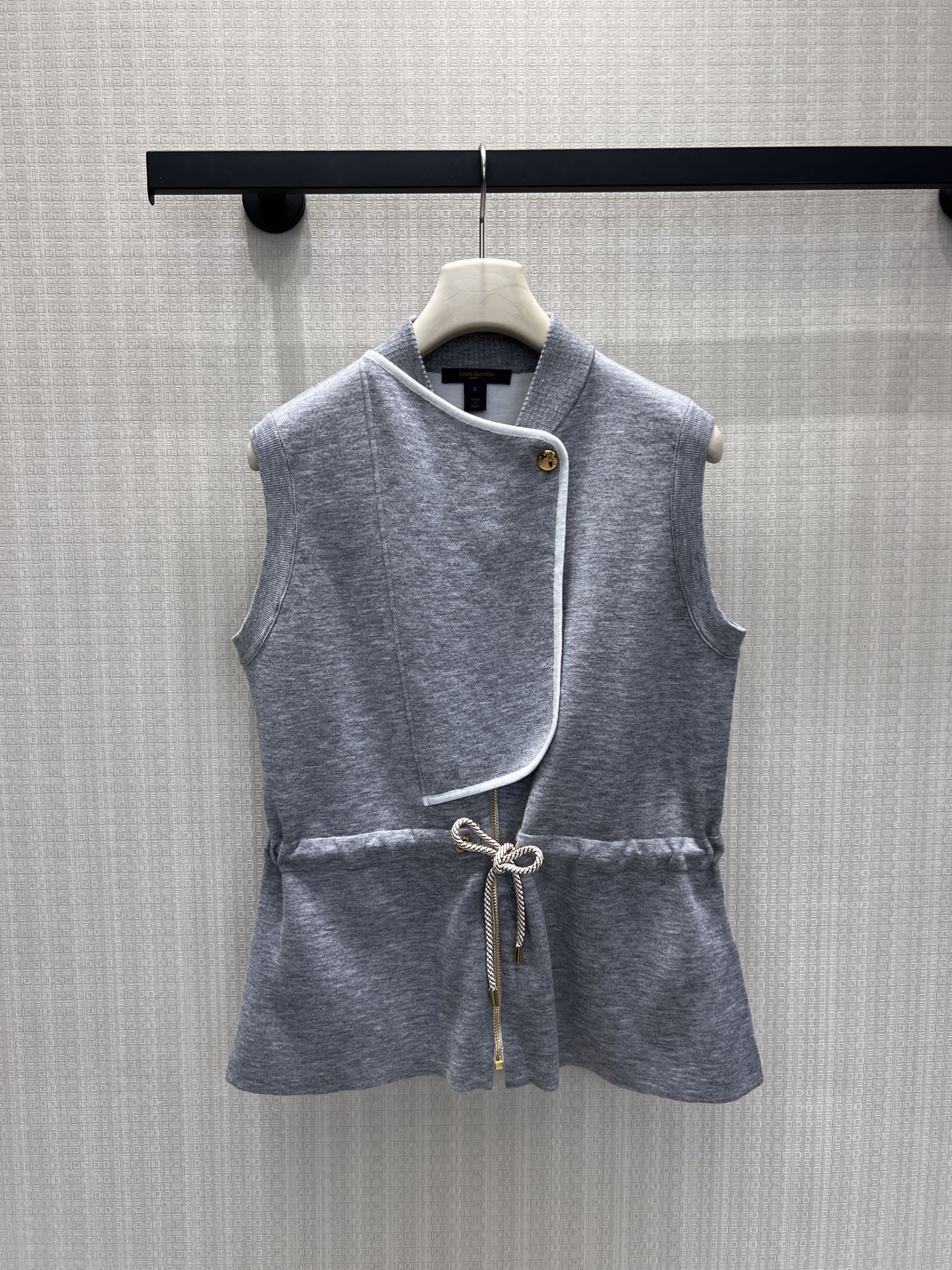 NO:878165,26 spring and summer new vest  Light gray knitted fabric blends a light luxury style, with a stand-up collar and a white edge slant placket design. The metal round buckle condenses the brand's exquisite texture. The waist drawstring can be freely adjusted to easily outline the waistline and optimize the proportion of the body shape. The hem naturally spreads out with a sense of relaxed layering. None  The sleeves are neatly and casually cut, and the soft, waxy, skin-friendly fabrics are selected to provide both warmth and flexibility. It can be worn with a shirt or a bottoming shirt, and can be worn for daily commuting and leisure travel to create a casual and high-end sense of big brands. Ready for sale smL,, shirts,1986090926春夏新品马甲 浅灰针织糅合轻奢格调,立领搭配白边斜襟设计,金属圆扣凝练品牌精致质感.腰部抽绳可自由调节版型,轻松勾勒腰线、优化身形比例,下摆自然散开自带松弛层次感.无袖剪裁利落随性,甄选软糯亲肤面料,兼具保暖与穿搭可塑性.内搭衬衫或打底衫皆可,日常通勤、休闲出行都能穿出大牌随性高级感.现货出售smL,,shirts,,Women's clothing