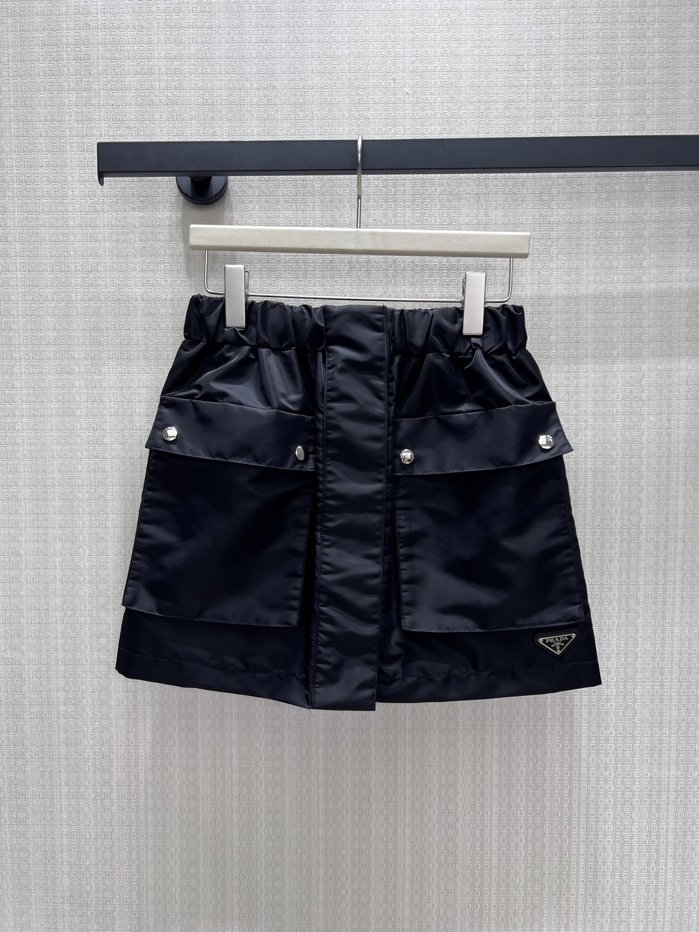 NO:884797,26 spring and summer new skirt Pra** classic nylon skirt, which combines workwear aesthetics with urban neatness. The crisp nylon fabric has a matte texture, the bud waistband is equipped with three-dimensional workwear pockets, and the silver rivets and triangular logo hide the brand genes. The neat short cut optimizes the proportions, has both a cool and high-end feel, and can easily create an effortless high-street look. Ready for sale smL, prada, skirts,1986090926春夏新款半裙 Pra**经典尼龙半裙,将工装美学与都市利落感融为一体.挺括尼龙面料自带哑光质感,花苞腰头搭配立体工装口袋,银色铆钉与三角徽标暗藏品牌基因.利落短款剪裁优化比例,兼具酷飒与高级感,轻松打造不费力的高街造型.现货出售smL,,prada,skirts,,Women's clothing