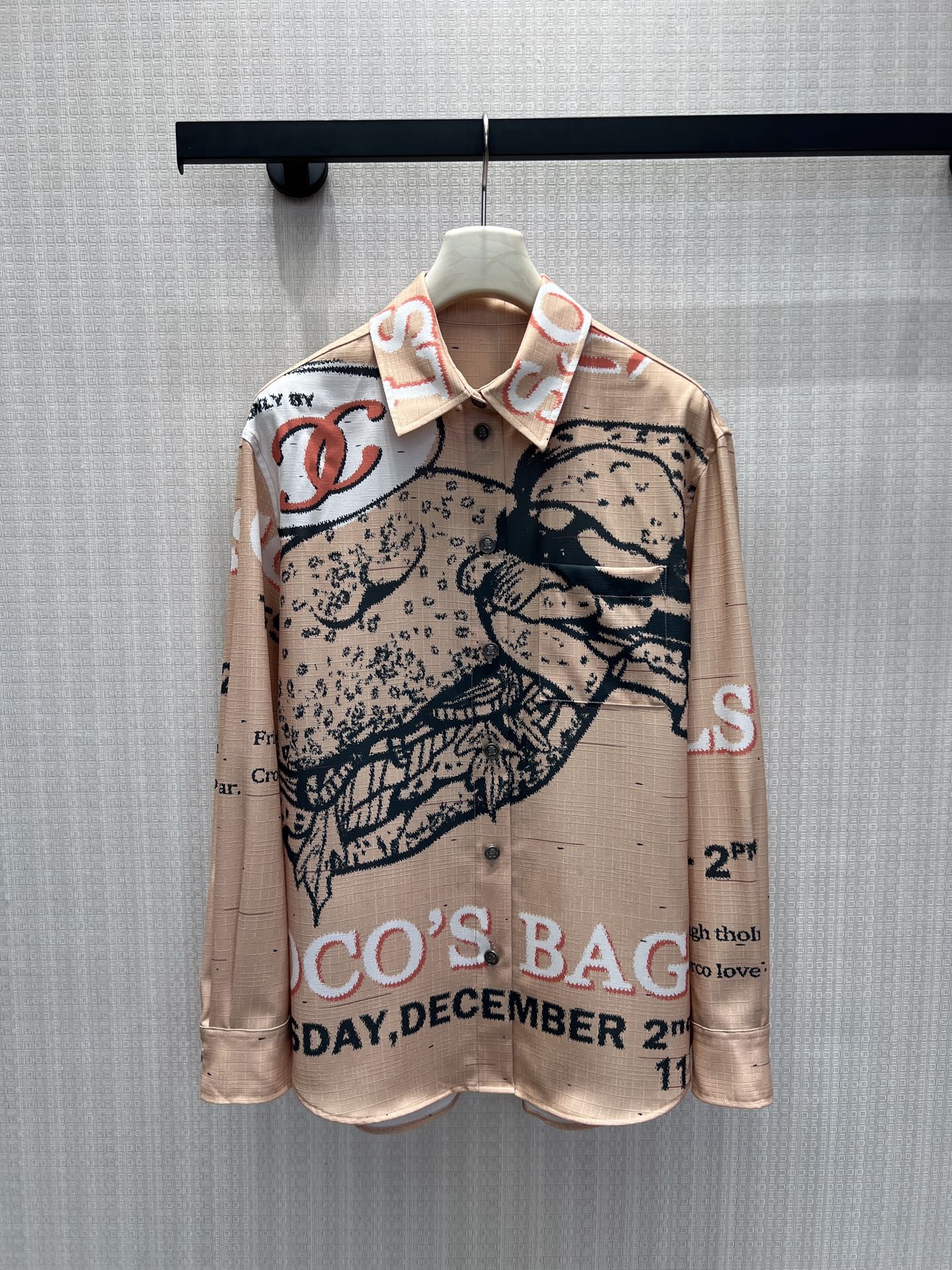 NO:893048,The new spring and summer 26 Cha** newspaper satin shirt has a gentle nude apricot background with retro newspaper art prints, hand-painted bags, and letter double C elements staggeredly arranged. The pixel texture replicates the texture of old newspapers and periodicals, creating a retro atmosphere.  The high-count draping satin material has a delicate and soft light, feels silky and is not easy to wrinkle, the classic lapels are matched with chest pockets, and the loose shoulder design hides the flesh and makes you look slimmer. Wear it alone, it is lazy and casual, and it is suitable for layering vests and suits. It blends retro literature and art with the brand's exquisite style. It is low-key and noble, and is a core item for daily commuting. In stock 36/38/40, shirts, business suit,1986090926春夏新款Cha** 报刊缎面衬衫 温柔裸杏底色铺展复古报纸艺术印花,手绘包袋、字母双C元素错落排布,像素肌理复刻旧报刊质感,复古氛围感拉满. 高支垂顺缎料自带细腻柔光,触感丝滑不易皱,经典翻领搭配胸前贴袋,宽松落肩版型藏肉显瘦.单穿慵懒随性,叠穿马甲、西装都适配,把复古文艺与品牌精致格调相融,低调显贵,日常通勤氛围感核心单品.现货36/38/40,,shirts,business suit,,Women's clothing