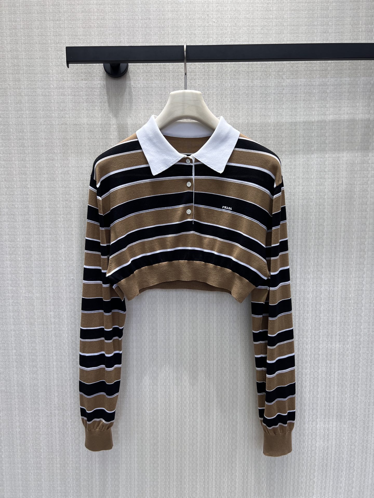 NO:893063,26 new spring and summer Miu** brown striped short Polo sweater,  The delicate thin knitted fabric is light and breathable, and the classic lapel half-button design is simple and attractive. The micro embroidered logo on the chest is low-key and restrained, the short wavy hem neatly raises the waistline, and the slightly loose long sleeves modify the arm lines. Pair it with off-white wide-leg pants to balance the skin exposure, and the retro contrasting stripes bring a relaxed atmosphere. Suitable for commuting and going out, this Italian retro short top is sweet and cool. In stock 36/38/40,, miumiu,1986090926春夏新品 Miu** 棕调条纹短款Polo针织衫, 细腻薄款针织轻盈透气,经典翻领半开扣设计简约耐看.胸口微型刺绣标低调内敛,短款波浪下摆利落拉高腰线,微宽松长袖修饰手臂线条.搭配米白阔腿裤平衡露肤度,复古撞色条纹自带松弛氛围感,通勤、出街都适配,甜酷交织的意式复古短上衣.现货36/38/40,,miumiu,,Women's clothing