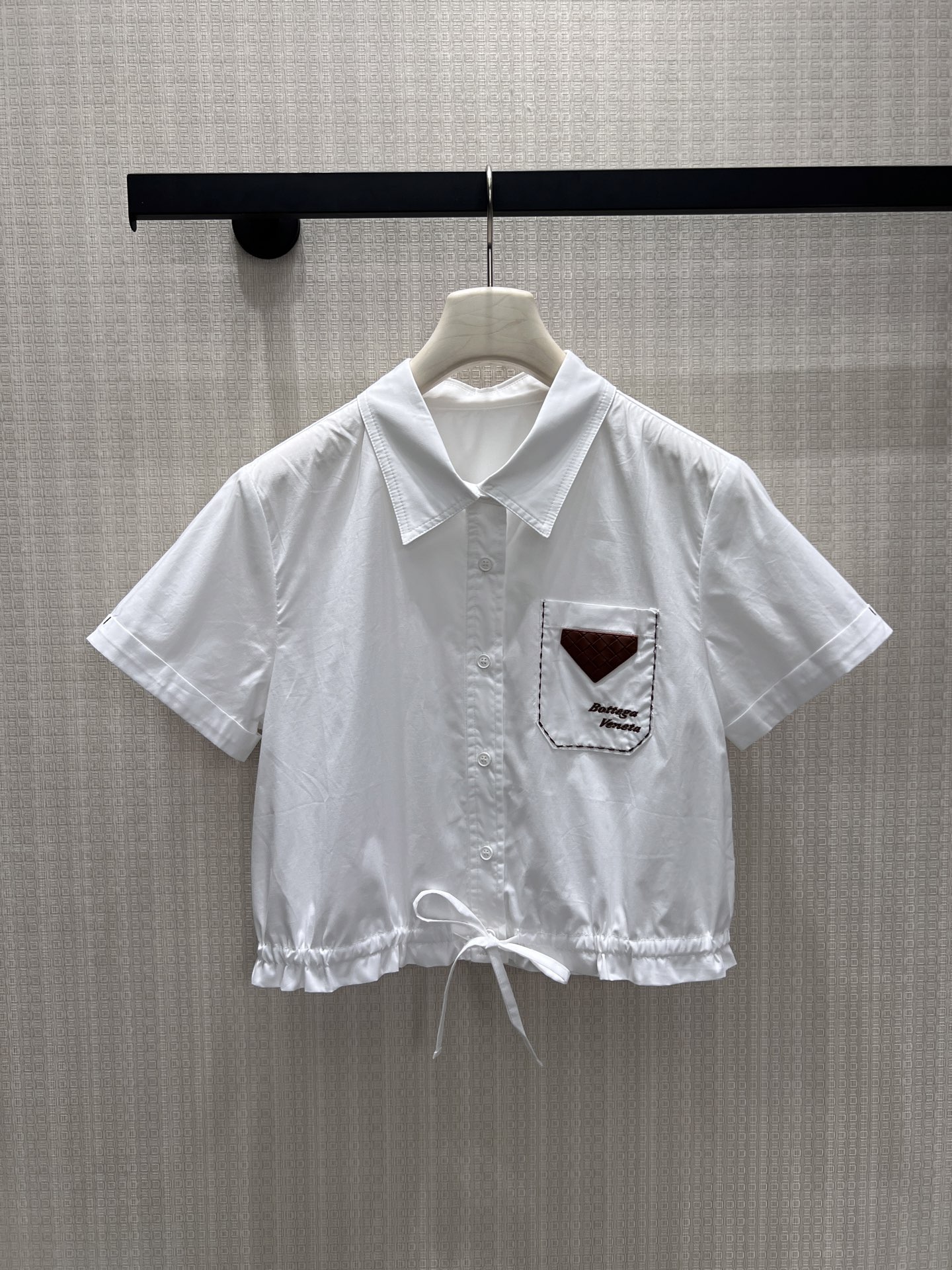 NO:908583,New Spring/Summer 26 Designer Shirt. Contrasting leather triangle patch pockets with embroidered logo, low-key Italian minimalist style. The single-breasted placket is simple and elegant, and the adjustable drawstring at the hem is a short-cut version, which can easily raise the waistline. The loose short-sleeved cut is body-friendly, and the clean white tone is versatile and does not choose bottoms. It is suitable for commuting and leisure. It combines casual relaxation and low-key luxury to create a simple and advanced daily look. Ready in stock smL  Actual detailed pictures, shirts, T-shirts,1986090926春夏新品 设计师款衬衫 撞色皮质三角贴袋搭配刺绣标识,低调释放意式极简格调.门襟单排扣简约大气,下摆可调节抽绳短裁版型,轻松拉高腰线.宽松短袖剪裁包容身形,干净白调百搭不挑下装,通勤休闲皆适配,糅合随性松弛与低调轻奢,打造简约高级日常造型.现货smL 实拍细节图,,shirts,T-shirt,,Women's clothing