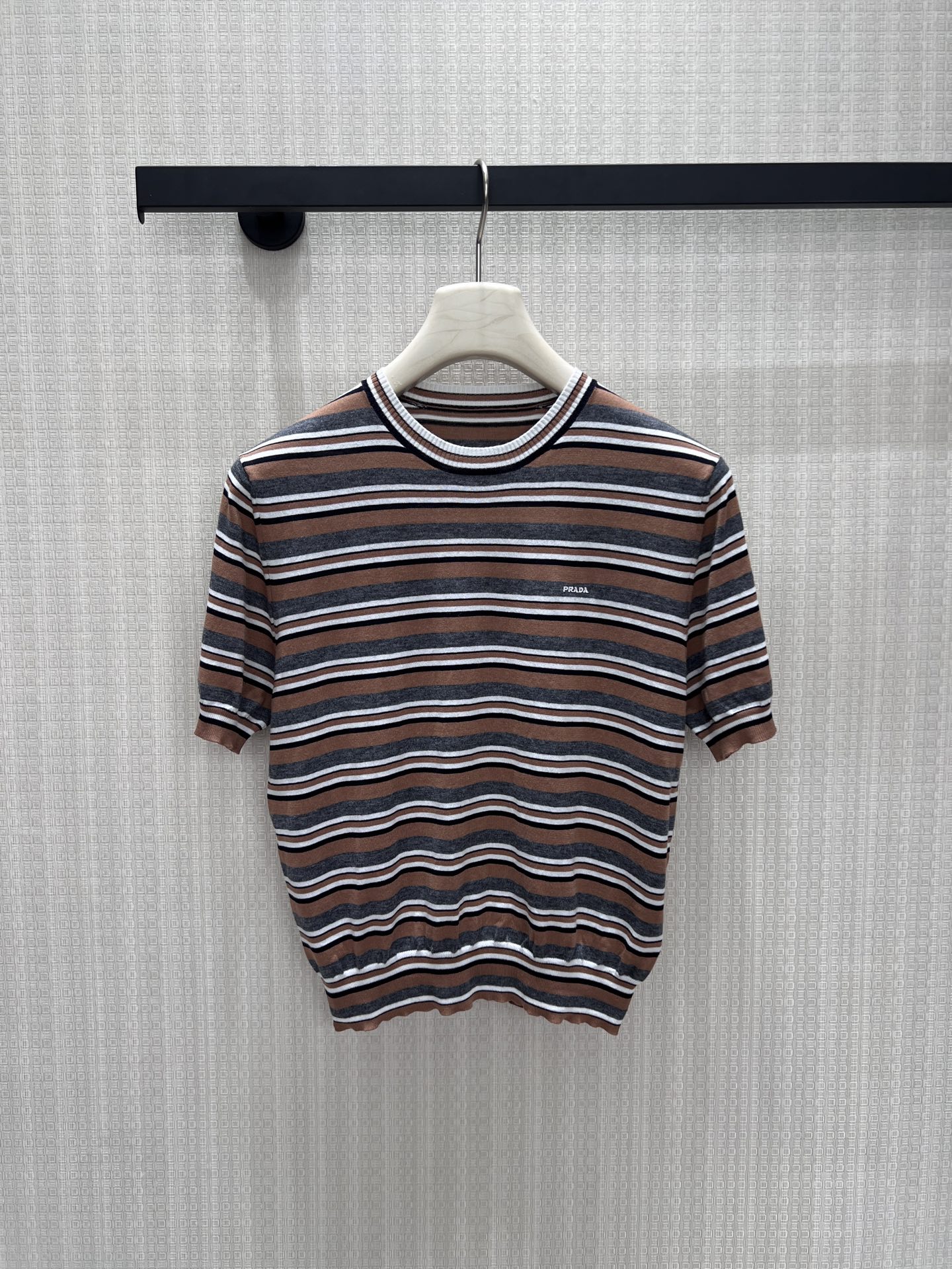 NO:912062,26 spring and summer new pra** striped knitted short-sleeves, caramel, charcoal gray and white thin strips intertwined, low-saturated color matching, soft and high-end. The contrasting round neck outlines the neat neck, fine and light knitting is breathable and skin-friendly, and the short hem optimizes the body proportions. The micro-brand embroidery on the chest is low-key and exquisite, with a sense of retro relaxation. It is refreshing when worn alone, and the layering of the inner suit is full, and it is easy to achieve a simple and durable light luxury commuting style. In stock 36/38/40  Actual detailed pictures, prada, T-shirt, business suit,1986090926春夏新款 pra**条纹针织短袖,焦糖、炭灰与白细条交织,低饱和配色柔和高级.撞色圆领勾勒利落脖颈,细密轻薄针织透气亲肤,短款收摆优化身材比例.胸口微型品牌刺绣低调精致,自带复古松弛感,单穿清爽、内搭西装层次感拉满,轻松拿捏简约耐看的轻奢通勤格调.现货36/38/40 实拍细节图,,prada,T-shirt,business suit,,Women's clothing