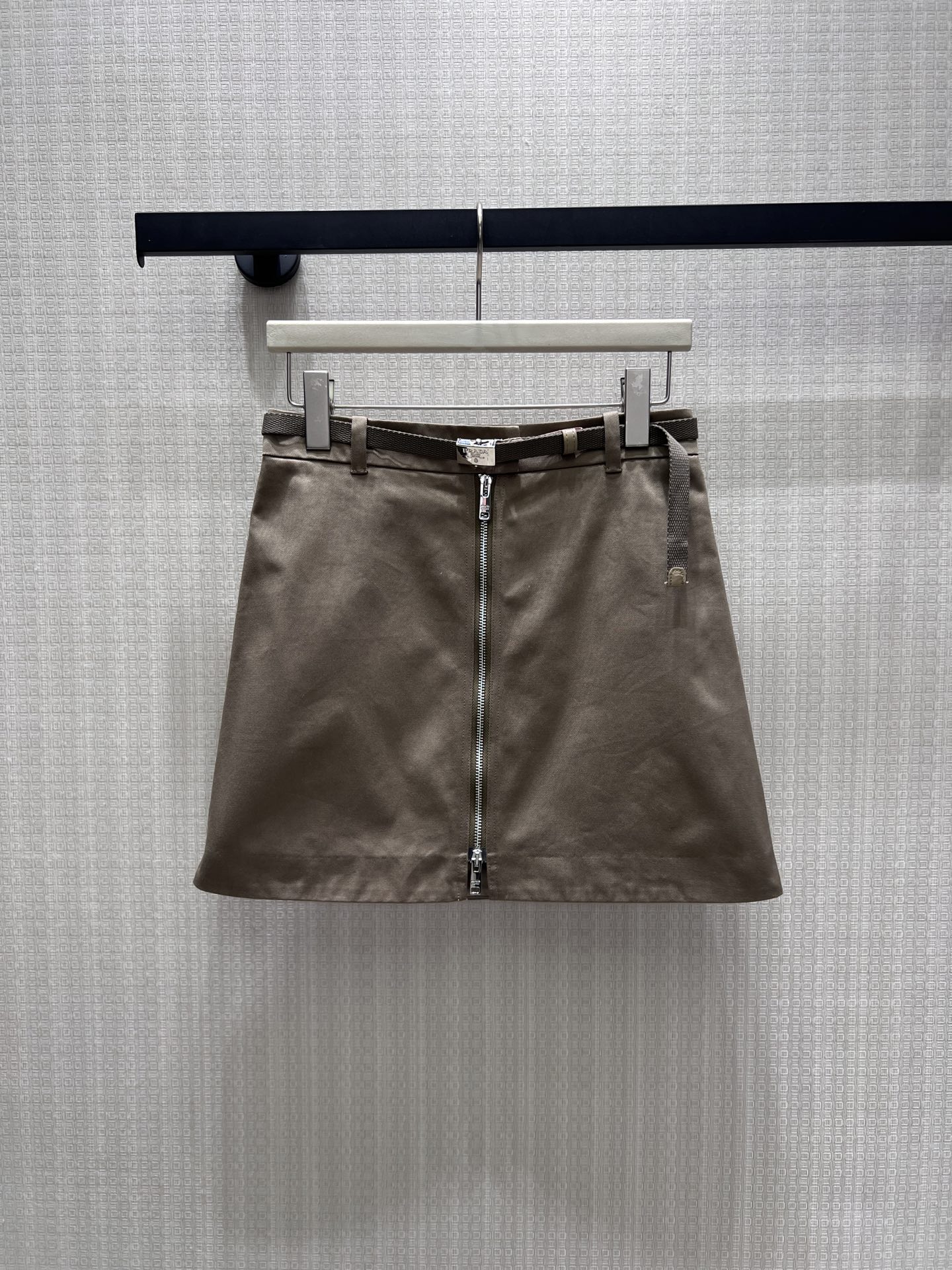 NO:933554,26th early autumn new product Pra** coffee color workwear A-line skirt, with a simple and capable Italian tone. It comes with a fine woven belt of the same color to embellished the waistline. The full-length metal zipper design on the front is neat and eye-catching. The neat A-line tailoring modifies the crotch and optimizes the leg lines. The crisp cotton fabric is not easy to deform, and the low-saturated coffee color is versatile and durable. It can be matched with shirts or knitted tops. It balances girlishness and coolness, making it easy to create a minimalist, light and luxurious look for daily commuting. Ready in stock smL  Actual detailed pictures, prada, skirts, shirts,1986090926早秋新品 Pra**咖色工装A字半裙,自带简约干练的意式调性.附赠同色系细织腰带点缀腰线,正面全长金属拉链设计利落吸睛,利落A字剪裁修饰胯部,优化腿部线条.挺括棉质面料不易变形,低饱和咖色百搭耐看,搭配衬衫、针织上衣均可,平衡少女感与清冷高级,日常通勤轻松打造极简轻奢造型.现货smL 实拍细节图,,prada,skirts,shirts,,Women's clothing