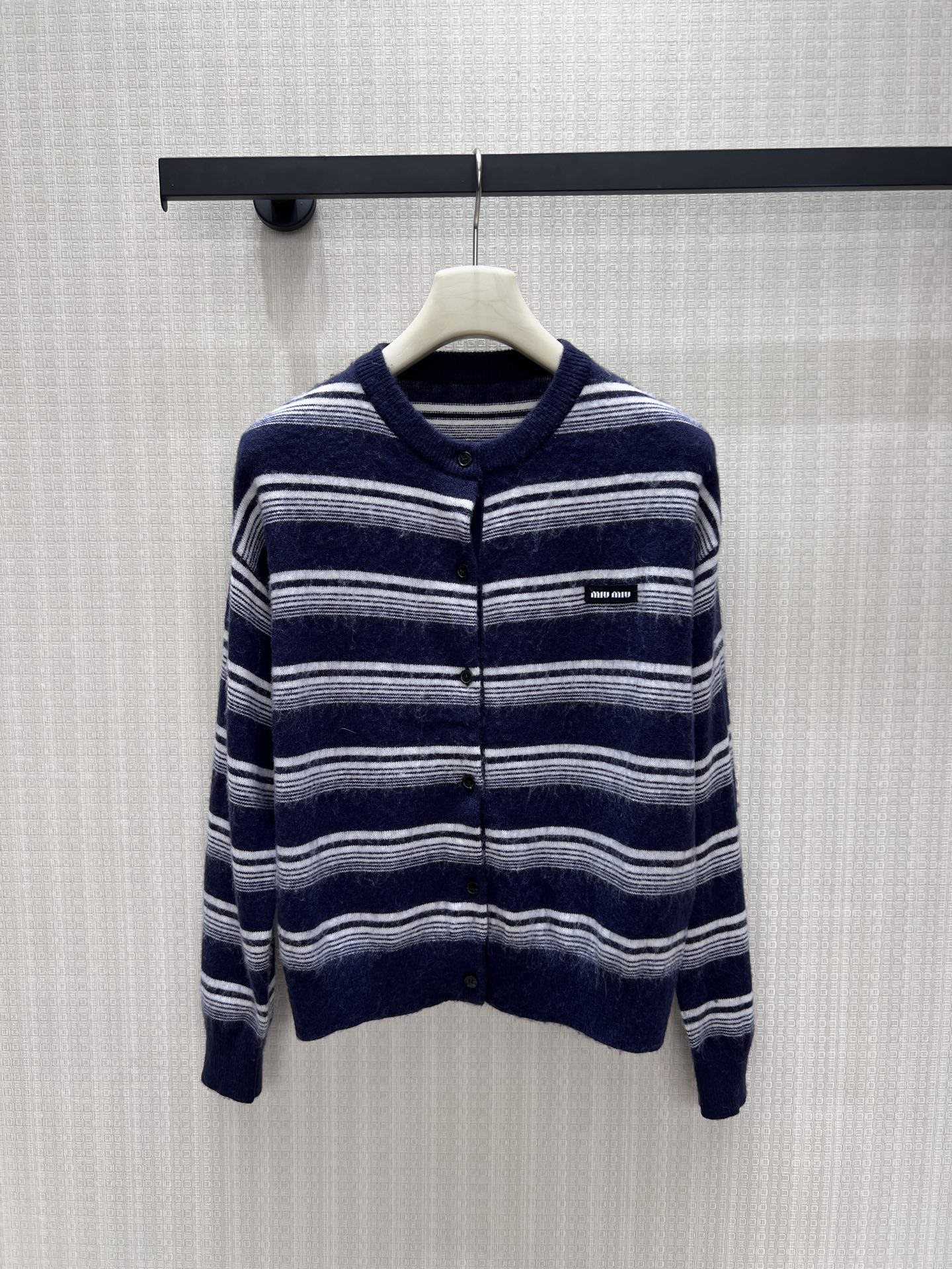 NO:950733,26 early autumn new product miu** wool cardigan  Navy blue and white horizontal stripes, with a hazy plush texture, full of atmosphere. Simple round neck with single-breasted button closure, easy to put on and take off, and the woven label on the chest is a low-key embellishment of the brand style. The short and neat version optimizes body proportions, and the lazy and loose tailoring accommodates the body shape. The retro college style is versatile and durable, can be worn alone or layered, and can easily create a cool and gentle light luxury daily look. Detailed photos of the real stock 36/38/40, miumiu,1986090926早秋新品 miu**羊毛开衫 藏青与白相间横条纹,自带朦胧毛绒质感,氛围感十足.简约圆领搭配单排扣开合,穿脱自在,胸口织标低调点缀品牌格调.短款利落版型优化身材比例,慵懒宽松剪裁包容身形.复古学院风格百搭耐看,单穿或叠搭内搭皆宜,轻松塑造清冷温柔的轻奢日常造型.现货36/38/40实拍细节图,,miumiu,,Women's clothing