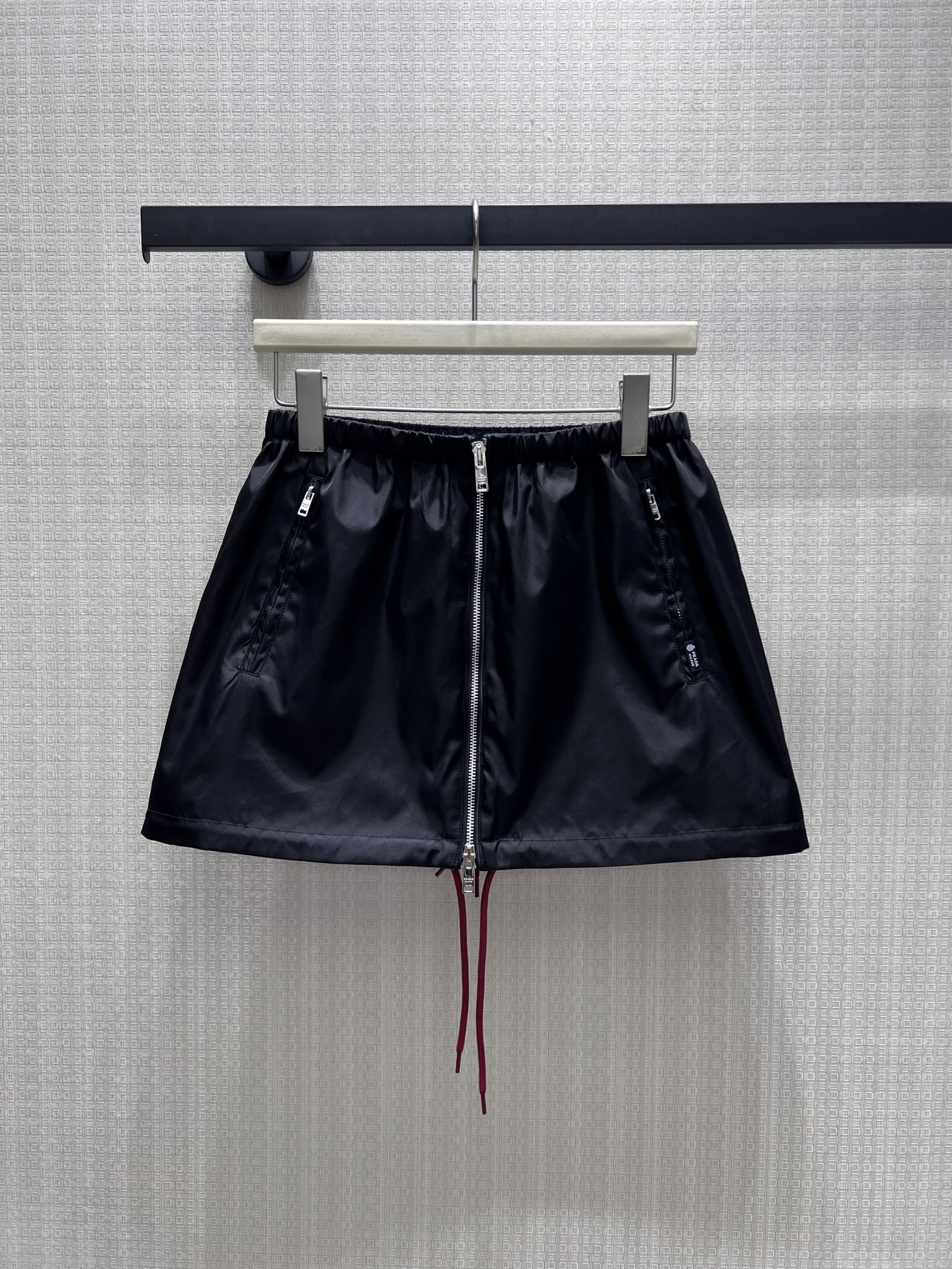 NO:958069,26th early autumn new product Pra** cool nylon functional style skirt, with a neat black base and burgundy drawstrings, and clever color gradation. The full-length zipper design on the front is highly recognizable, and the zipper pockets on both sides are both beautiful and practical. The elastic waistband adapts to a variety of waistlines, the A-line shape modifies the crotch, and the fabric is crisp and smooth. Mix and match sweatshirts and short tops to create a casual and avant-garde street luxury look. Ready in stock smL  Actual detailed pictures, prada,hoodie,sweatshirts,skirts,1986090926早秋新品 Pra**酷感尼龙机能风半身短裙,利落黑色基底碰撞酒红抽绳,色彩层次巧妙点睛.正面全长拉链设计极具辨识度,两侧拉链口袋兼顾美观与实用性.松紧腰头适配多种腰围,A字版型修饰胯部,面料挺括顺滑.混搭卫衣、短上衣皆出彩,打造随性前卫的街头轻奢造型.现货smL 实拍细节图,,prada,hoodie,sweatshirts,skirts,,Women's clothing