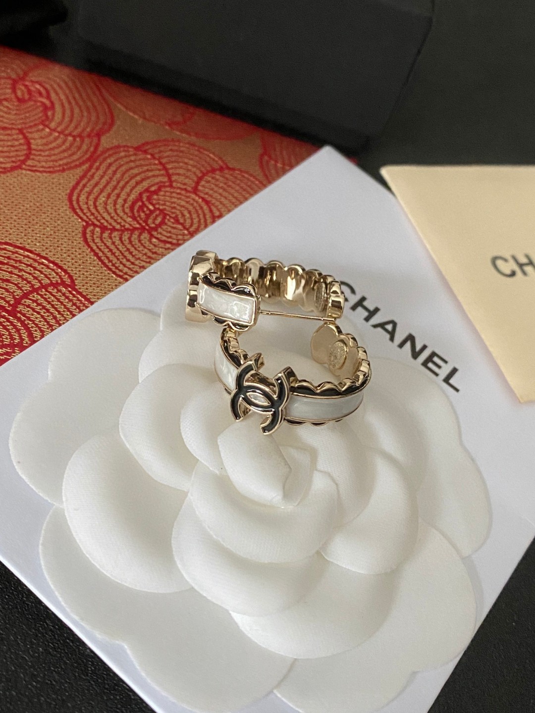 💘CHANEL新款24b精雕花边圆环耳环👍以白色琉璃搭配圆形耳圈图案，周边黑色琉璃点缀花朵纹路。复古又显