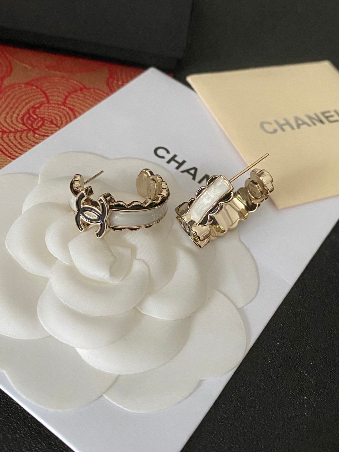 💘CHANEL新款24b精雕花边圆环耳环👍以白色琉璃搭配圆形耳圈图案，周边黑色琉璃点缀花朵纹路。复古又显
