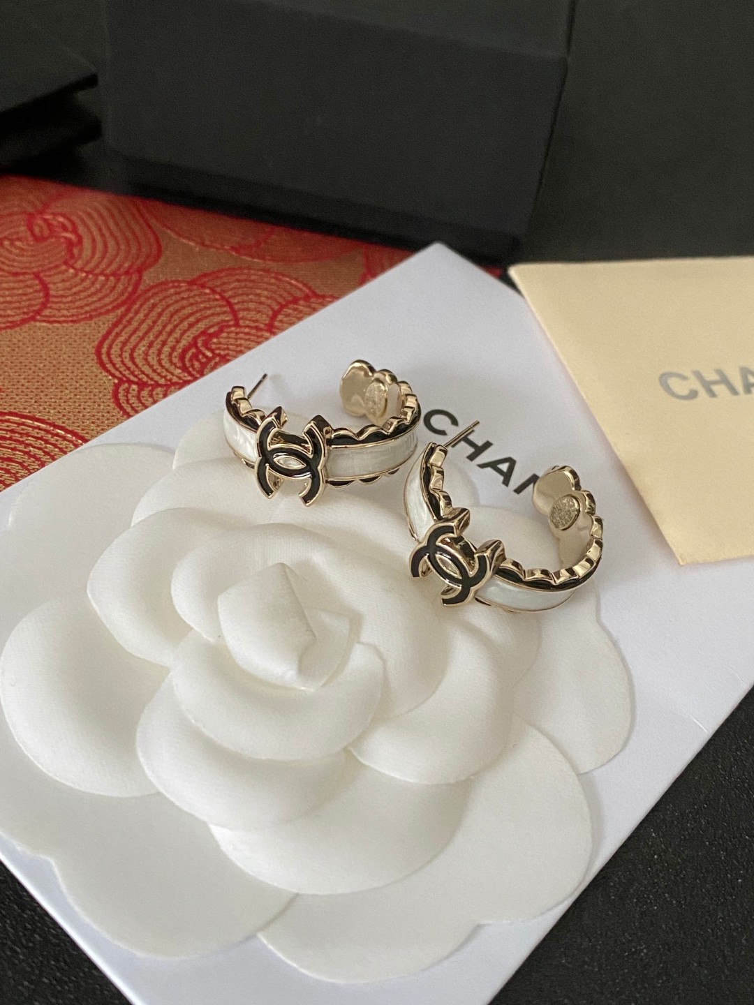 💘CHANEL新款24b精雕花边圆环耳环👍以白色琉璃搭配圆形耳圈图案，周边黑色琉璃点缀花朵纹路。复古又显