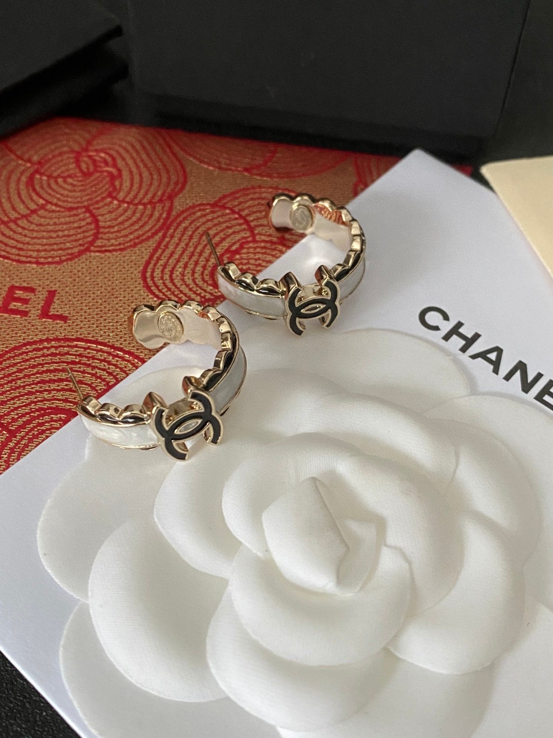💘CHANEL新款24b精雕花边圆环耳环👍以白色琉璃搭配圆形耳圈图案，周边黑色琉璃点缀花朵纹路。复古又显