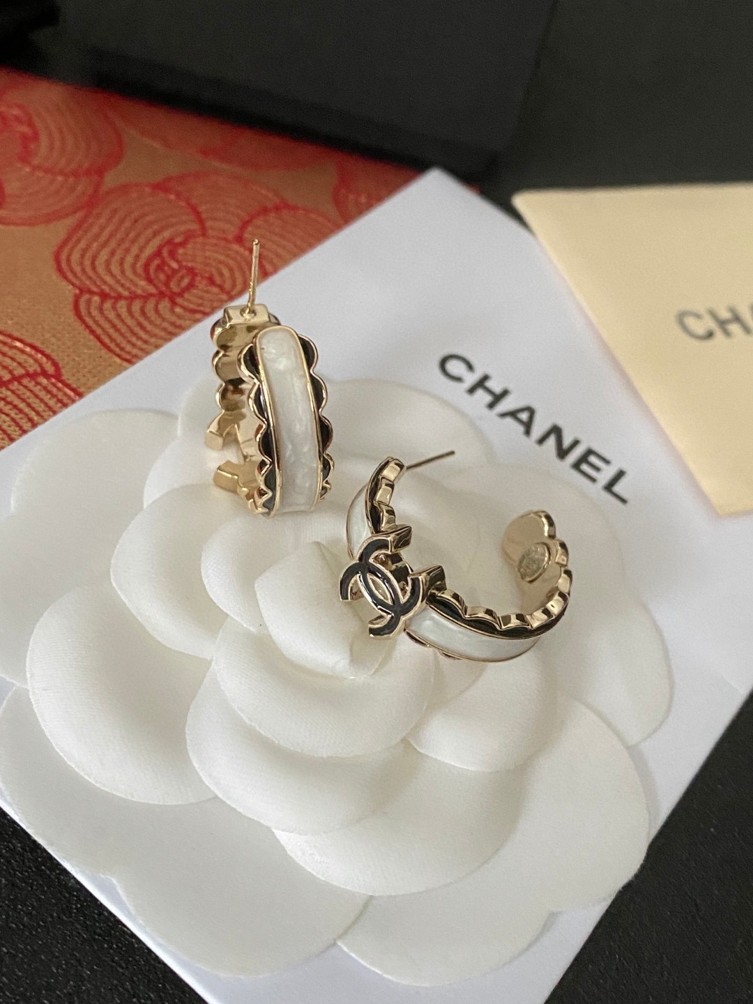 💘CHANEL新款24b精雕花边圆环耳环👍以白色琉璃搭配圆形耳圈图案，周边黑色琉璃点缀花朵纹路。复古又显