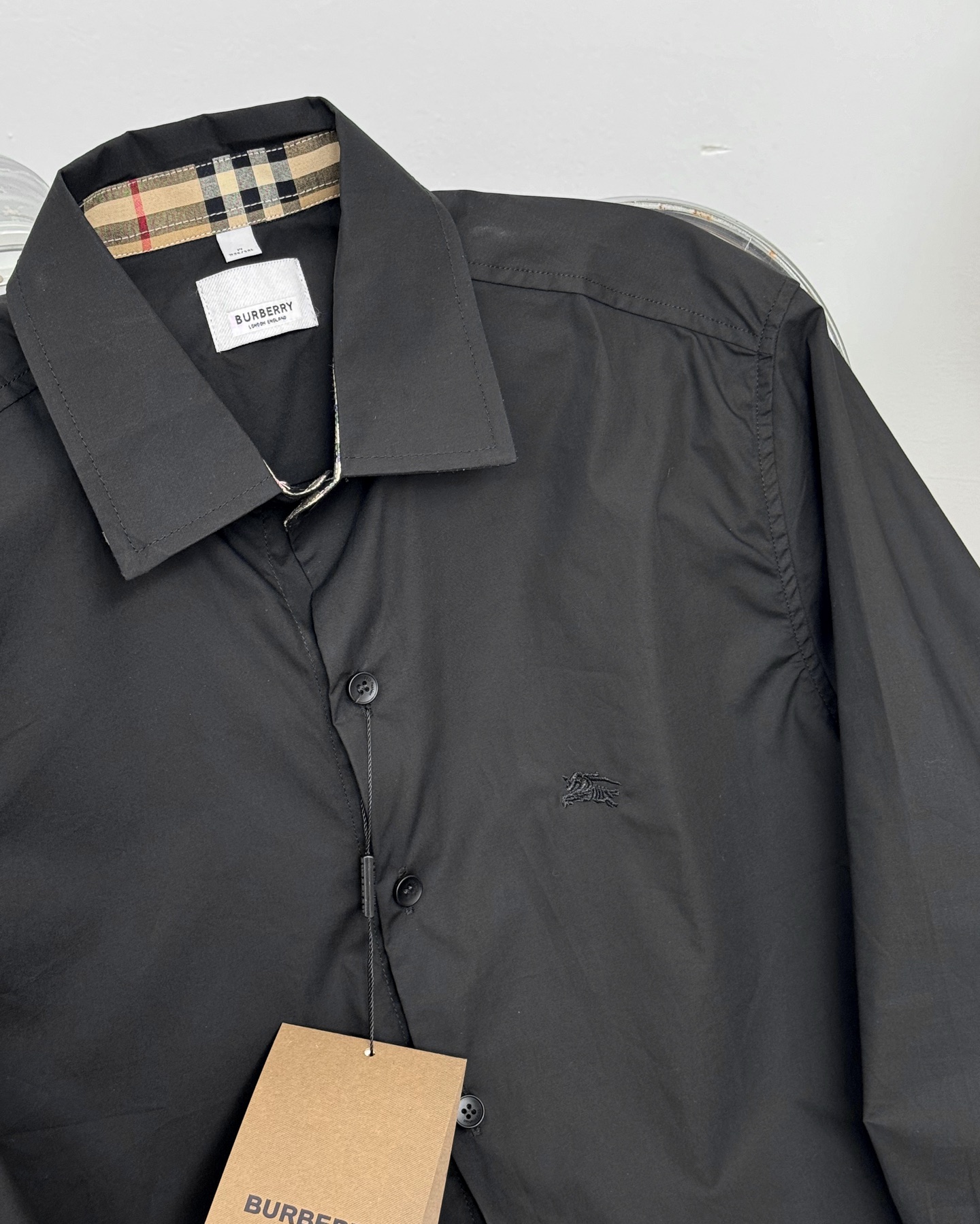💰125     巴宝莉 BURBERRY25ss战马徽标刺绣长袖衬衫

     领口袖口经典格子相拼 显得极为精致时尚也为平淡的色系 增加了一丝看点，胸前小战马字母刺绣标识 辨识度极高

    辅料：开模原版过鉴定领标➕正品代购级原版吊牌➕配套吊绳➕3D吊粒
工艺：原版一致走线！袖窿对版手法 最高版本！无数次的打版 百分百还原正品品相！

    正确版本 男女同款 超级显眼 超级好看 超级大气！无论是日常休闲商务都可轻松驾驭

颜色:黑色 白色  藏青色

尺码:S M L xl  xxl

           S      M	  L	      XL	      XXL	
衣长	75.5  .76.5.	  77.5	79.5	81.5	
胸围	106   110	  114.    118      122	
肩宽	48.	   49.	   50.	 51	      52	
袖长	63.	   64.      65     66       67
