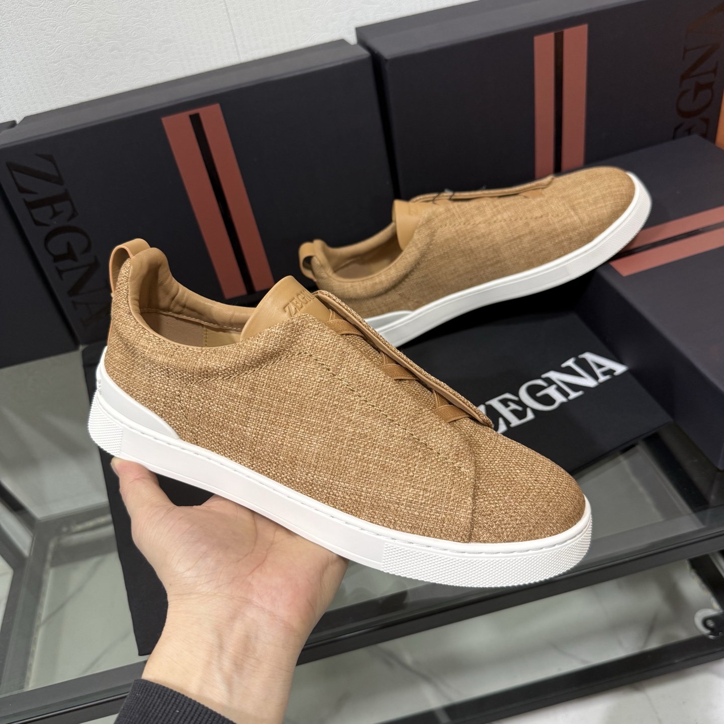 Zegna/杰尼亚 SECONDSKIN Triple Stitch&trade; 休闲运动鞋，帆布系列
这款低帮运动鞋的鞋面光滑柔软。饰以标志性三重交叉松紧细节，致敬品牌精裁夹克的手工缝制工艺。设计轻盈，与白色橡胶鞋底相得益彰，专为快节奏的生活方式打造。这款鞋汲取手套制作灵感，融汇世代工匠经验智慧，选用新西兰顶级小牛皮制作，成就轻盈质地，精致衬里结合非凡韧性。带来独一无二的贴合感。非常轻盈的橡胶外底上点缀双条纹 Logo 运动细节，以超轻结构重新诠释标志性鞋款。领口部位鹿皮面料反车做法，无内裡车中底套楦做法。易穿脱套脚交叉松紧带和 3D&ldquo;波纹&rdquo;设计。鞋舌热压品牌名称。
后跟加贴 TPU 双条纹品牌 Logo 饰条，鞋身空胶做法，周圈加车大底缝线。轻盈的高弹力橡胶外底背面和可拆卸脚床饰 Zegna 标识，为这款运动鞋增添现代动感气息。
皮鞋码数:39/40/41/42/43/44/45/46/47 
专柜包装，现货